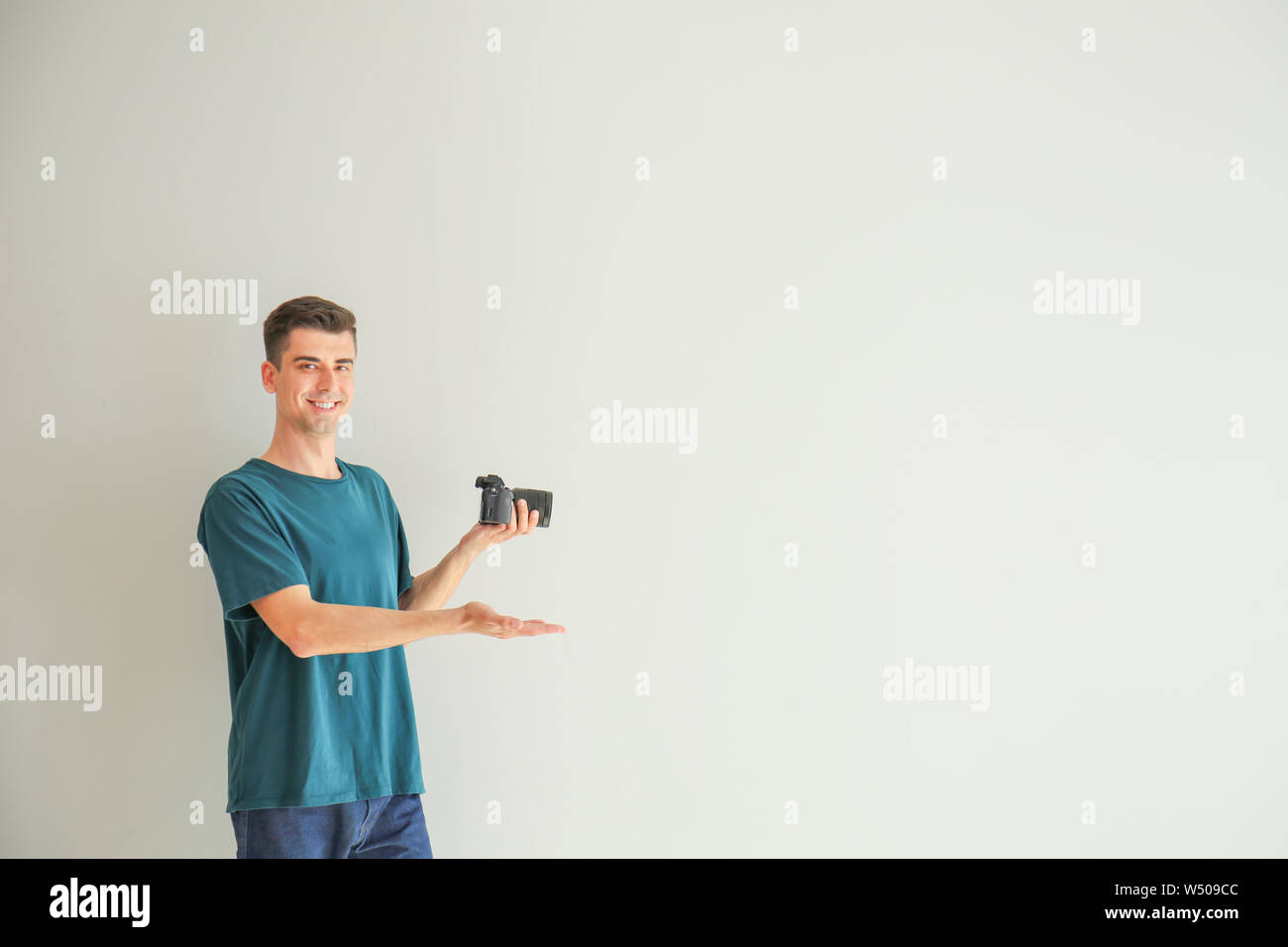 Männliche Fotograf zeigt auf etwas auf hellen Hintergrund Stockfoto