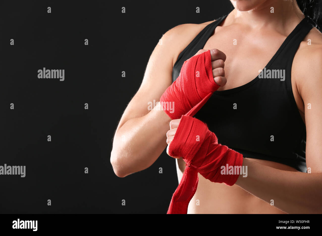 Sportliche weiblichen Boxer Anwendung Armbänder gegen den dunklen Hintergrund Stockfoto