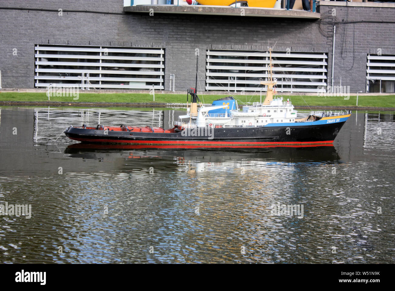 Touristen wie die Replik von Niederlande Schiff in der Freizeitpark Madurodam in Den Haag, Nederland, die auf einer Skala von 1 gebaut worden war: 25 zu sehen Stockfoto