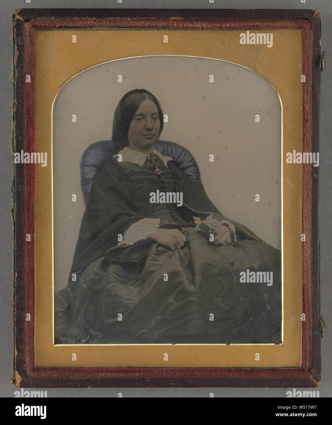 Bildnis einer sitzenden Frau mittleren Alters, die eine Blume, Thompson & Wagstaff (Briten, aktive London, England 1855 - 1856), 1855-1860, Ambrotype, von Hand gefärbt, 10 × 8,6 cm (3 15/16 x 3 3/8 Zoll Stockfoto