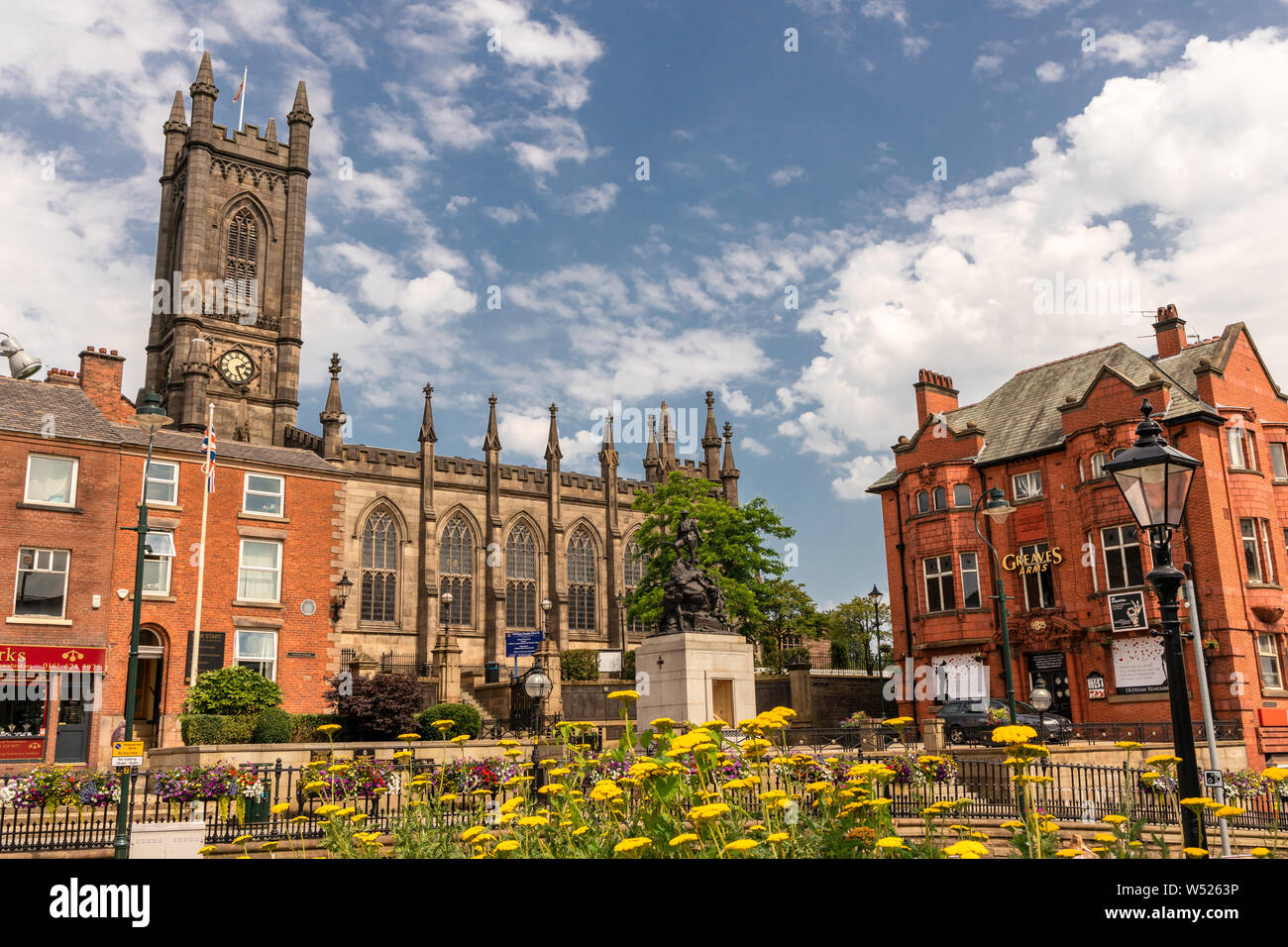 Stadtbild von Oldham Stadtzentrum mit Oldham Pfarrkirche und Kriegerdenkmal mit Sommer Blumenbeete und Körbe. Stockfoto