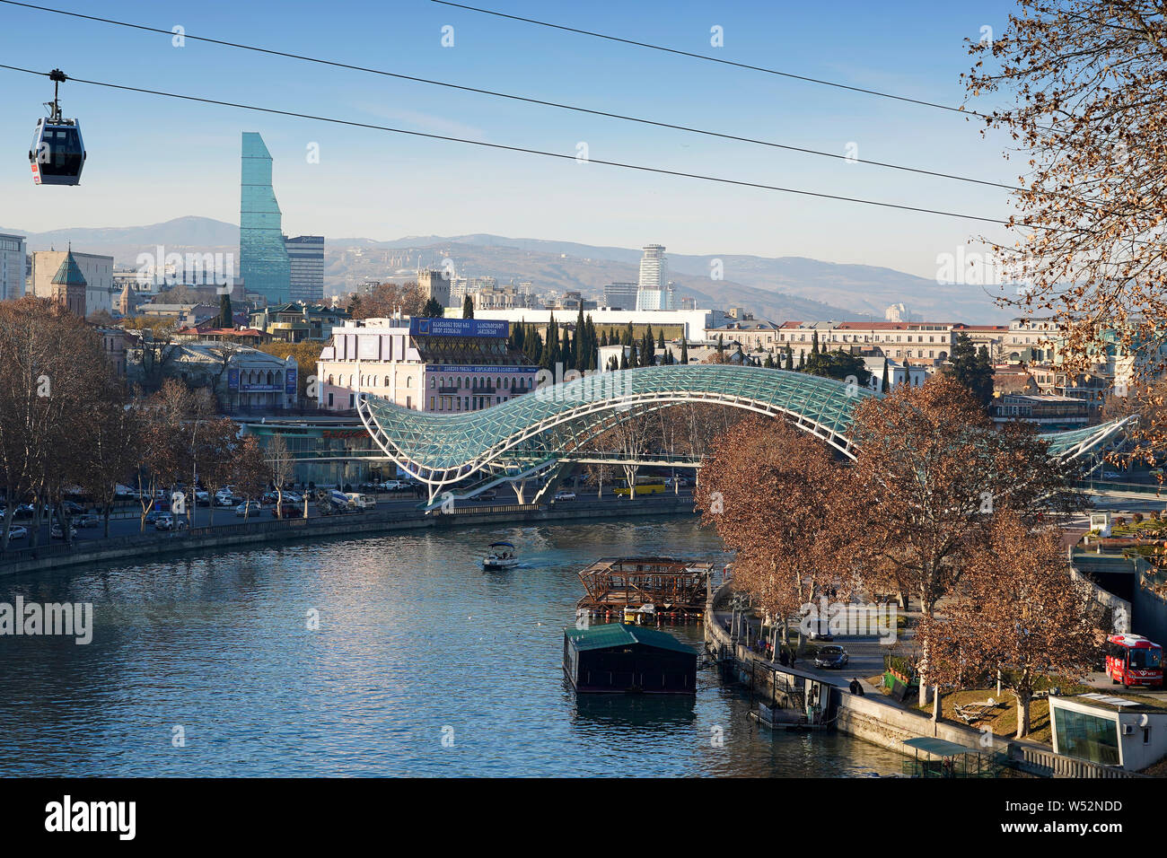 Eine Seilbahn Gondel schwebt über dem Mtkvari River. Im Hintergrund: die Brücke des Friedens von Michele De Lucchi. Der Innenstadt von Tiflis, Georgien, Kaukasus Stockfoto