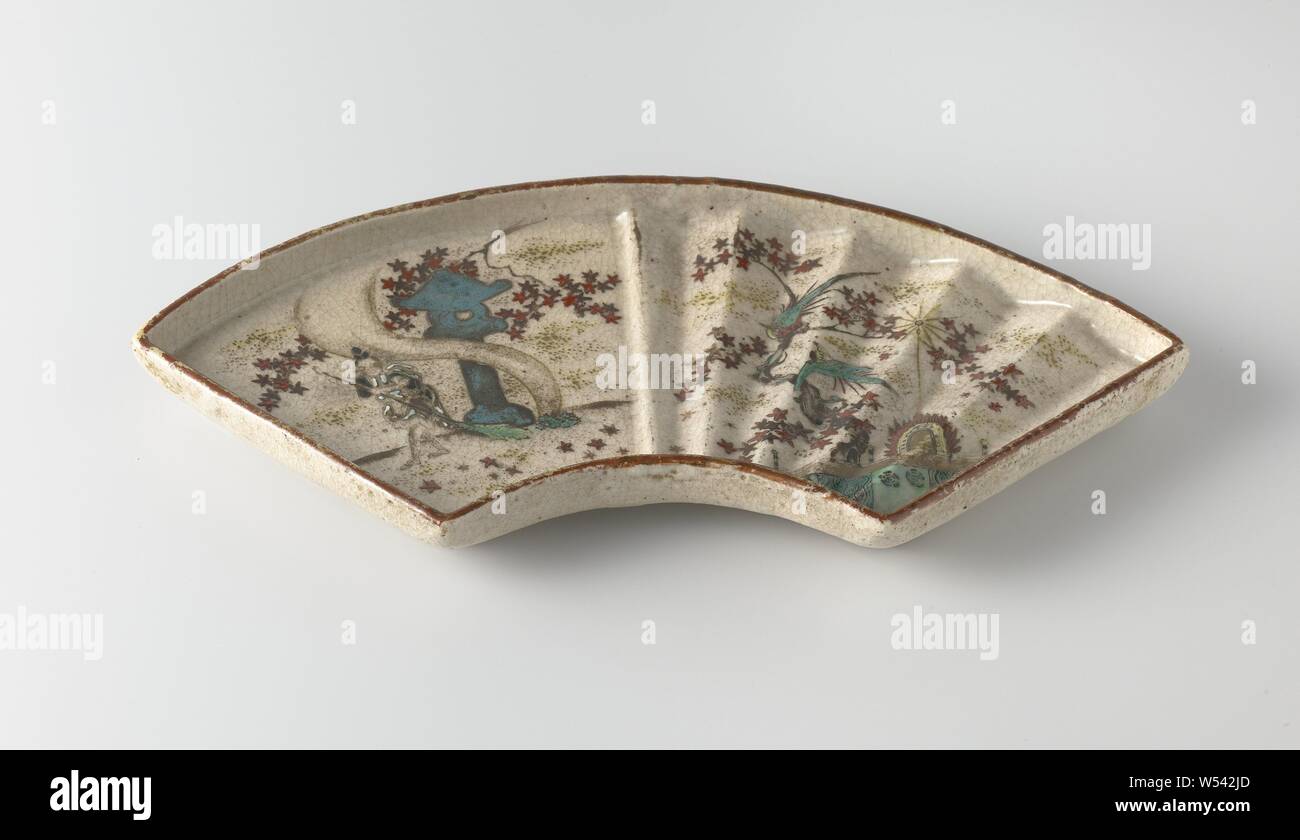 Fächerförmige Gericht mit einer Abbildung, blühende Pflanzen und Vögel, Fächer, Behälter aus Steinzeug, malte auf der Glasur in Blau, Rot, Grün, Gelb, Braun, Schwarz und Gold. Die Hälfte der Unterseite mit geformte Rippen, die andere Hälfte ist glatt. Auf dem rutschigen eine halbe Person mit einem Besen fegt Blätter für eine Struktur- und Blütenpflanzen (Ahorn?). Die andere Hälfte mit zwei Vögel auf einem blühenden Pflanze in der Nähe eines Gebäudes. Unten sind vertikale Dekorative Bänder. Drei alte Aufkleber auf der Unterseite mit 'Owari. Shino-yaki / Die 18 Cent zutreffend als "Zierpflanzen mit golddust und Designs von Pflanzen etc. / Alexander beschrieben. Stockfoto