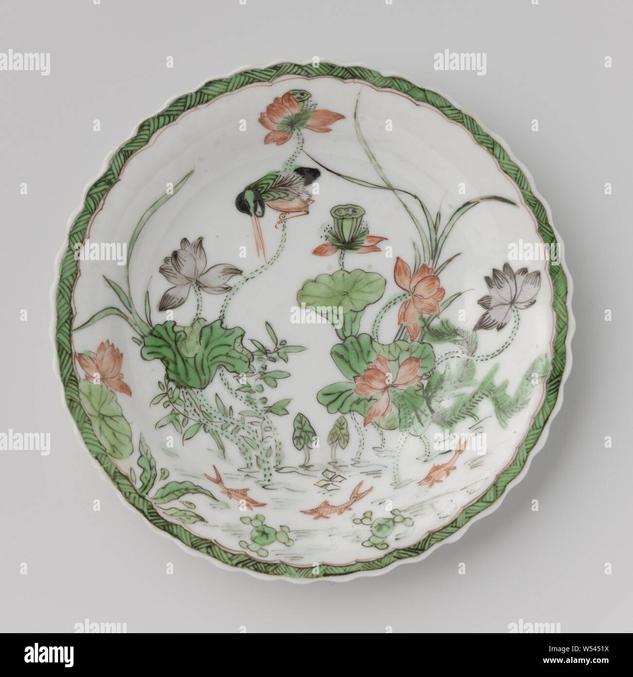 Untertasse mit einem Teich, Lotus Pflanzen, Fische und Vögel, Porzellanschale mit gelappten, in unterglasur Blau und auf der Glasur Rot, Grün, Gelb, Aubergine und Schwarz lackiert. Auf der Platte des Tellers einen Teich mit Lotus Pflanzen, drei Fischen und einen Eisvogel, den Rand mit Zickzack, auf der Rückseite drei Blume Sprays. Teller auf der Unterseite mit einer Dichtung in einem doppelten Kreis markiert. Famille Verte., anonym, China, C. 1700 - C. 1724, Qing- Dynastie (1644-1912)/Kangxi-Periode (1662-1722)/Yongzheng-Periode (1723-1735), Porzellan (Material), Glasur, Cobalt (Mineral), Verglasung, h 2 cm d 13cm d 6,8 cm Stockfoto