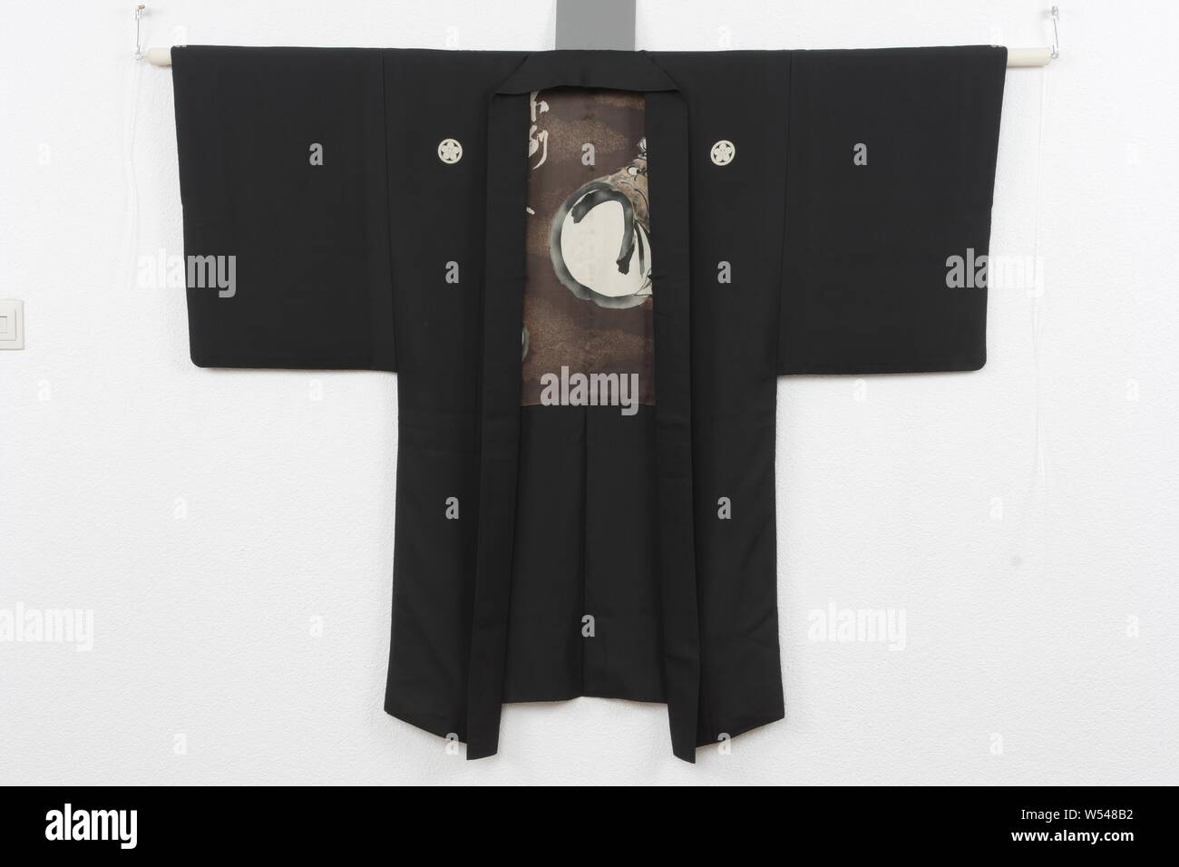 Männer haori mit Daruma Puppen, Haori für einen Mann mit einer Dekoration auf dem Futter von drei Daruma Puppen und der Text: "Futo futo suiro' (A Haze von trinken, er nicht umfallen, 'Roryukan Shonen Senshi hitsu' ('durch Roryukan Shonen Senshi" lackiert), seal'S honen'. Design für Kalligraphie und Malerei möglicherweise von Suzuki Shonen (1849-1918). Schwarz glänzende Seide (habutae) mit Dekoration in stenciled yuzen. Fünf Familienwappen (mon) von prunus blühen., anonym, Japan, 1920-1940, Seide, Malerei, h 133 cm x W107 cm Stockfoto