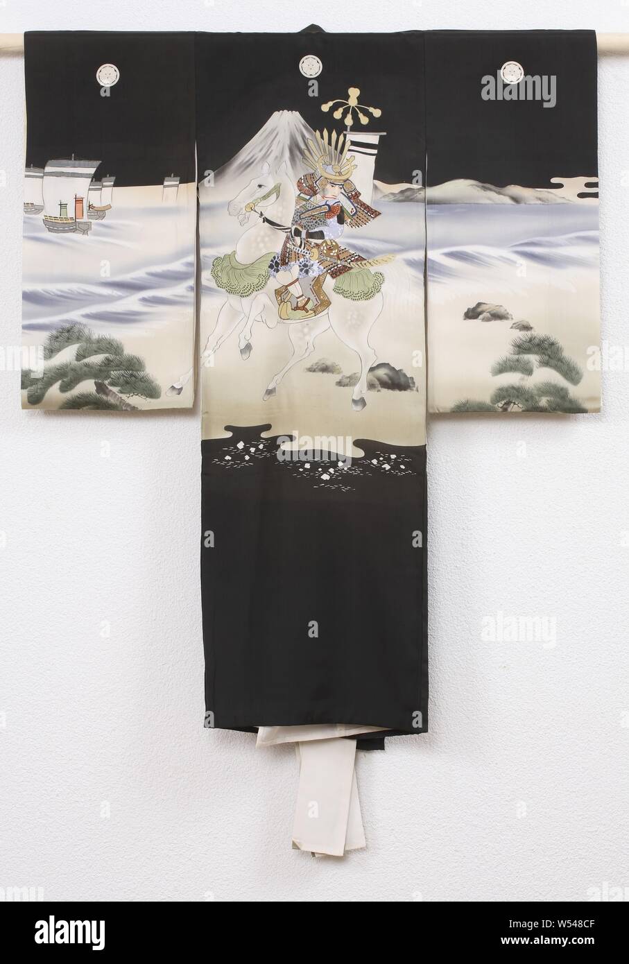 Jungen miyamairi Kimono mit der Schlacht des Fuji Fluss, Formal kimono für einen Jungen für den ersten Besuch in einem Shinto Schrein (miyamairi Kimono), mit einer Dekoration einer Nacht Szene mit einem Samurai auf dem Pferd am Ufer des Fuji Fluss, die Berge und die Schiffe im Hintergrund. Wahrscheinlich eine Szene aus der Schlacht von Fuji Fluss in 1180. Schwarze Seide mit einem gemalten yuzen Dekoration mit gesticktem Detaillierung und Blattgold. Weißer Seide gefüttert. Fünf Familie Waffen (mon) Der sauerampfer (katabami)., anonym, Japan, 1920-1940, Seide, Malerei, h 103 cm x W 85 cm. Stockfoto