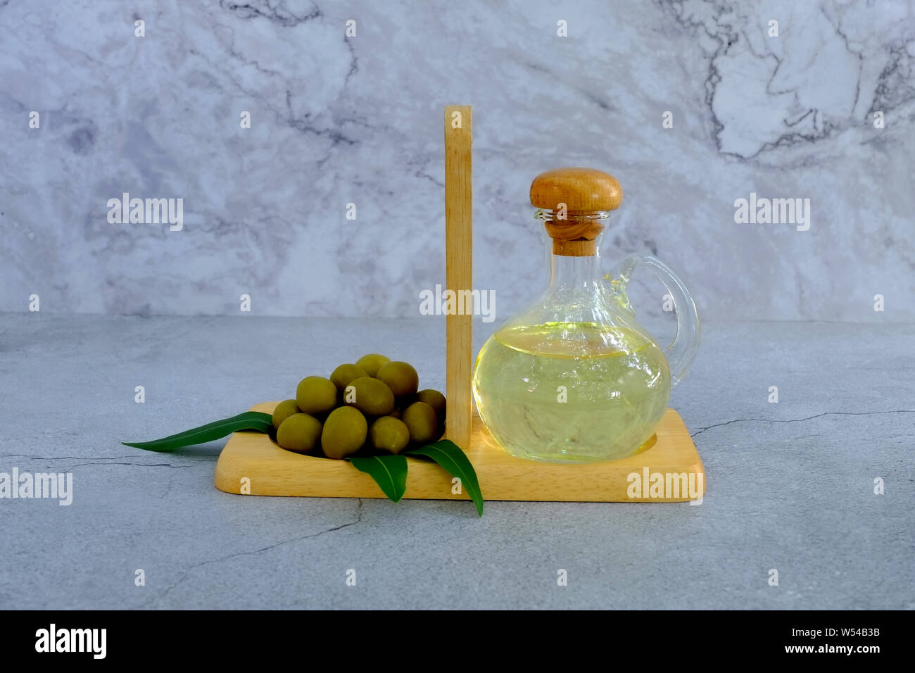 Satz von Olivenöl und Blatt auf Marmor Hintergrund, Glasflasche mit Olivenöl auf Zement, Glas Flasche premium natives Olivenöl Stockfoto