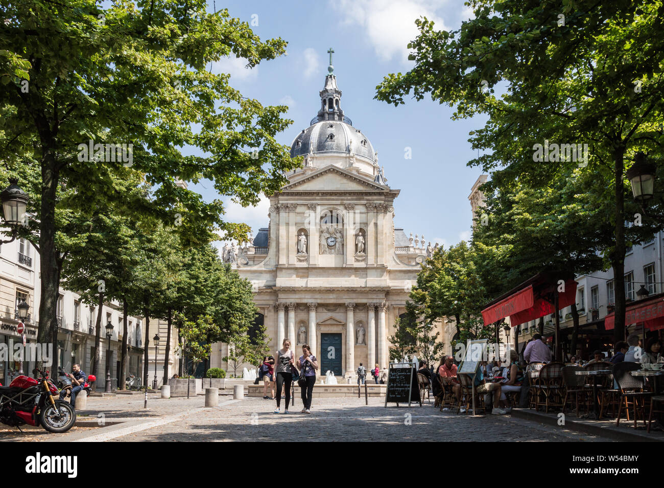 Horizontale Ansicht der Fassade der Universität Sorbonne mit Bäumen und Restaurants umgeben. Touristen zu Fuß in der Nähe Stockfoto