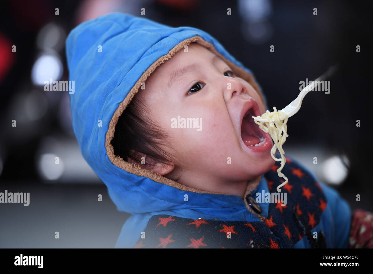 ---- Ein wenig chinesischer Junge ist Instant Nudelsuppe von seinen Eltern gefüttert, da Sie für Ihren Zug warten nach Hause für das chinesische Mondjahr während des Th zu gehen Stockfoto