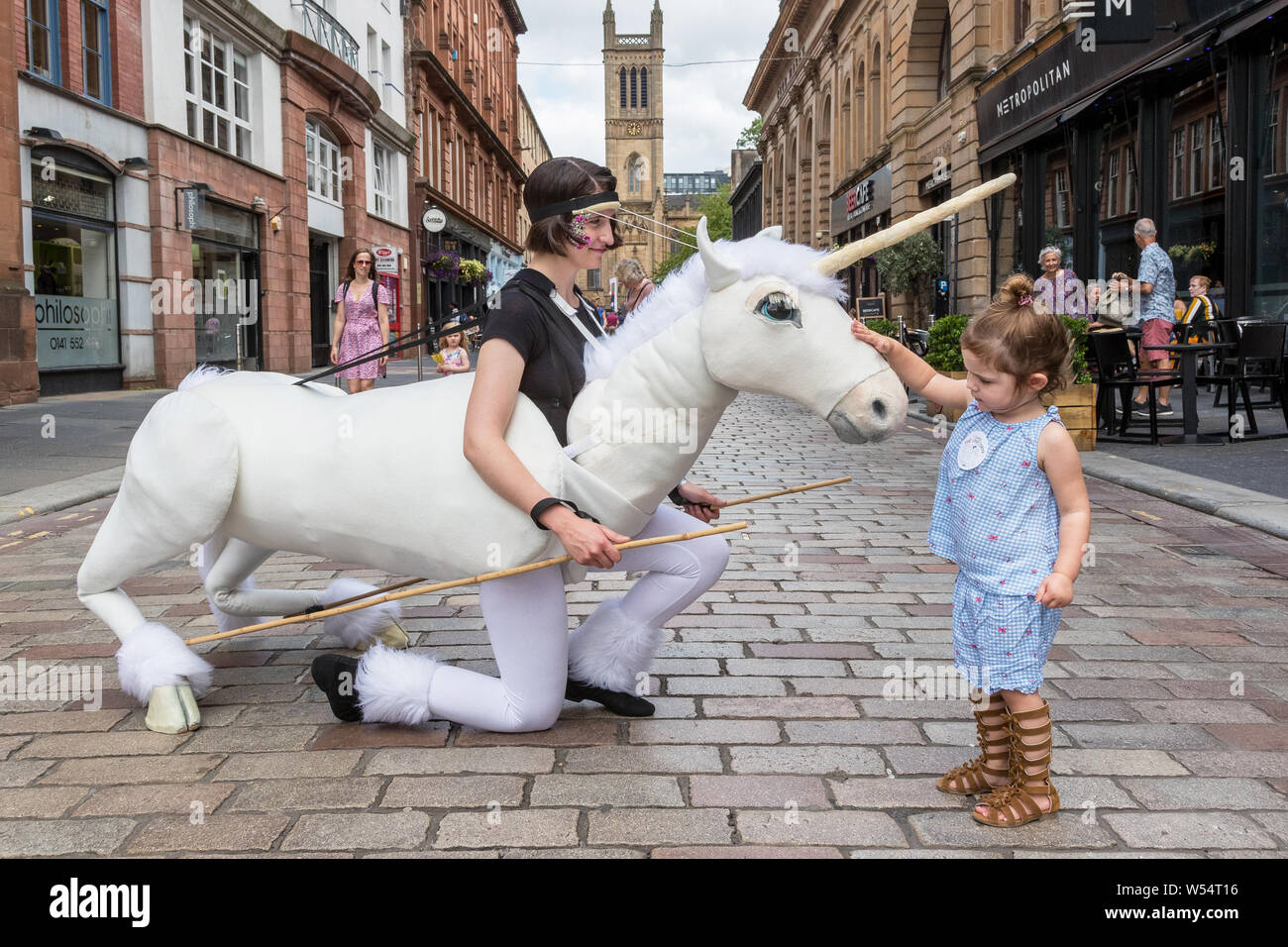 Glasgow, UK. 26. Juli 2019. Glasgow's jährliche grösste Festival der freien Straße Unterhaltung zieht Tausende von Touristen und Zuschauer mit der Merchant City District Street Theater, mime-Performances, Musik und Puppenspiel über einen dreitägigen Wochenende zu genießen. Zwei Jahre alten CHARLEY CAIRNS aus Airdrie wird durch das Einhorn Puppentheater fasziniert. Credit: Findlay/Alamy leben Nachrichten Stockfoto