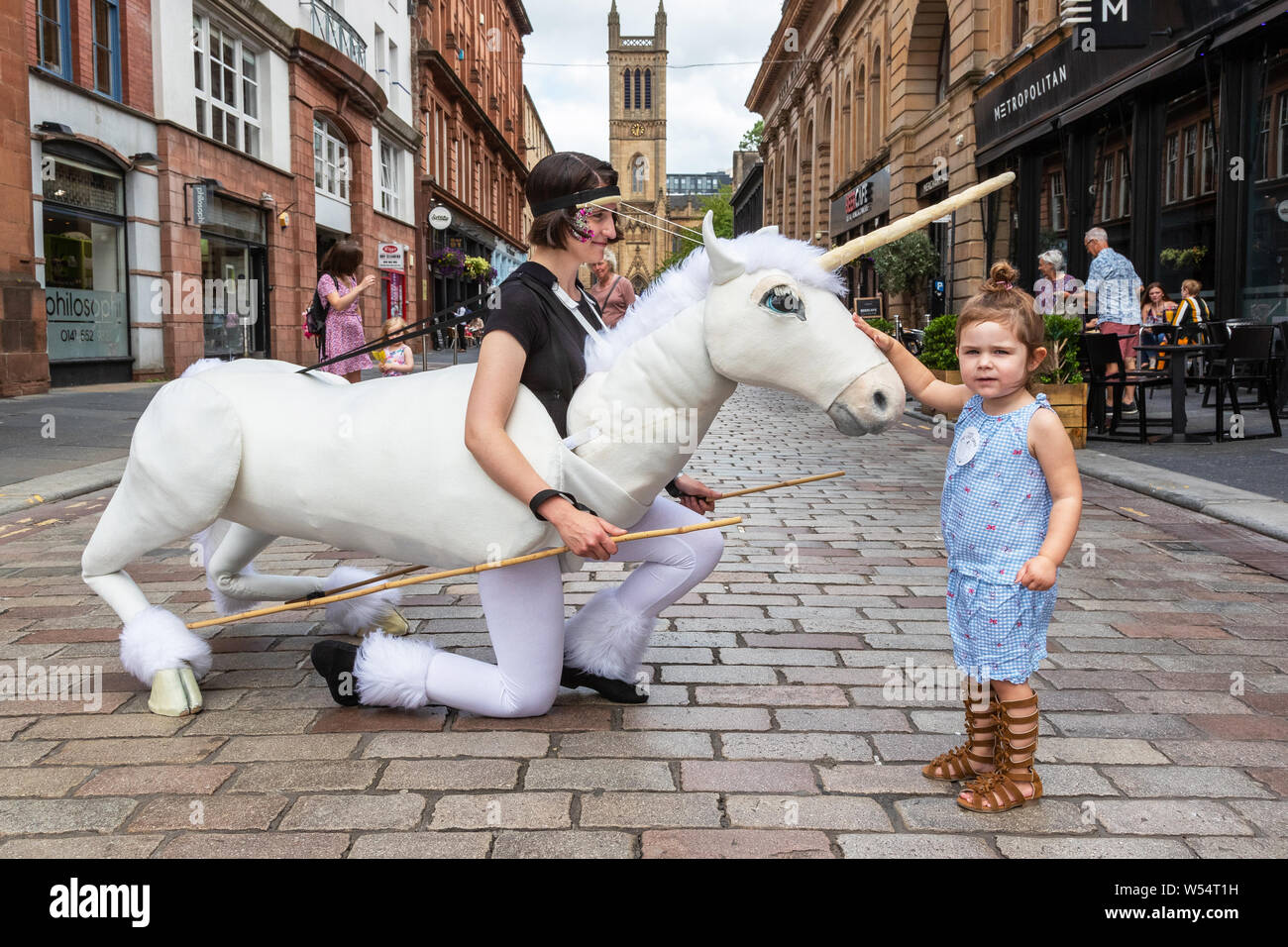 Glasgow, UK. 26. Juli 2019. Glasgow's jährliche grösste Festival der freien Straße Unterhaltung zieht Tausende von Touristen und Zuschauer mit der Merchant City District Street Theater, mime-Performances, Musik und Puppenspiel über einen dreitägigen Wochenende zu genießen. Zwei Jahre alten CHARLEY CAIRNS aus Airdrie wird durch das Einhorn Puppentheater fasziniert. Credit: Findlay/Alamy leben Nachrichten Stockfoto