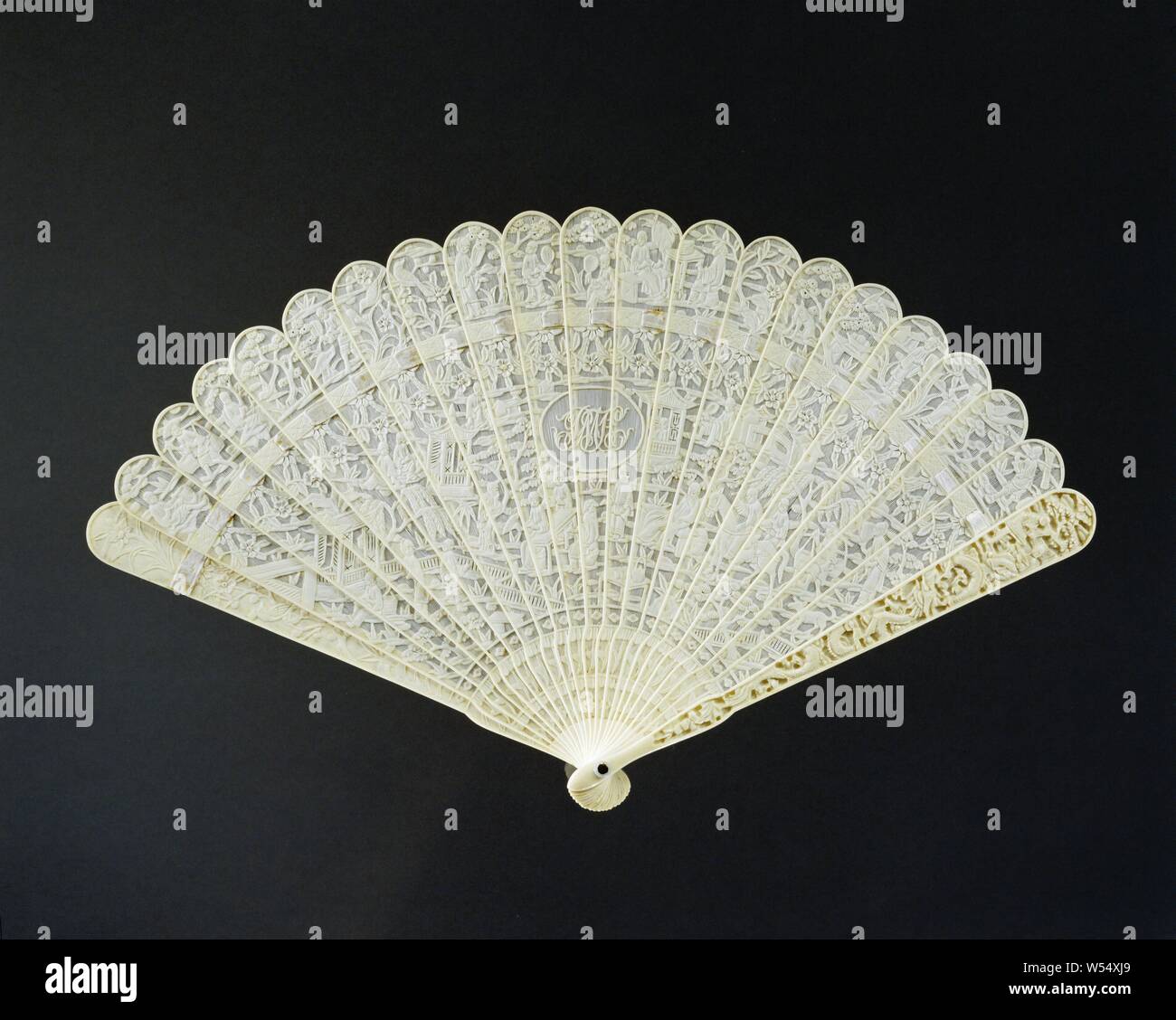 Brisé fan von Elfenbein, Abblendlicht geschnitzt, geprägten chinesischen Szenen auf beiden Seiten, ein Monogramm mit Pmh in der Mitte der Center, chinesischen Szenen in der Entlastung ausschneiden, in der Mitte ein Monogramm mit PMH. Die 21 zusammenhängenden Beine in der Entlastung werden mit einem Satinband gehalten. Die beiden äußeren Beine mit Drachen in Relief geschnitzt. Perlmutt Scheibe mit Sicherungsstift., anonym, Kanton, C. 1830 - C. 1840, montuur, schijfje, sluitpin, Fussel, Schneiden, s 31,5 cm x L 19 cm Stockfoto