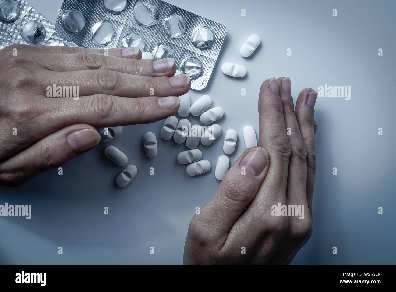 Hände Abdeckungen und versteckt viele weiße verschreibungspflichtige Medikamente, Medizin-Tabletten oder Vitamin Pillen in einem Stapel - Begriff des Gesundheitswesen, Opioide sucht, Scham Stockfoto