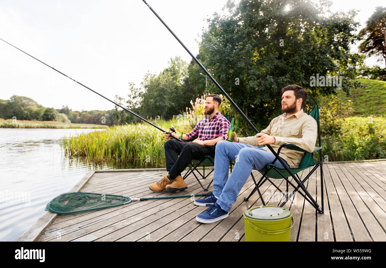 Männliche Freunde Angeln und Bier trinken auf See Stockfoto