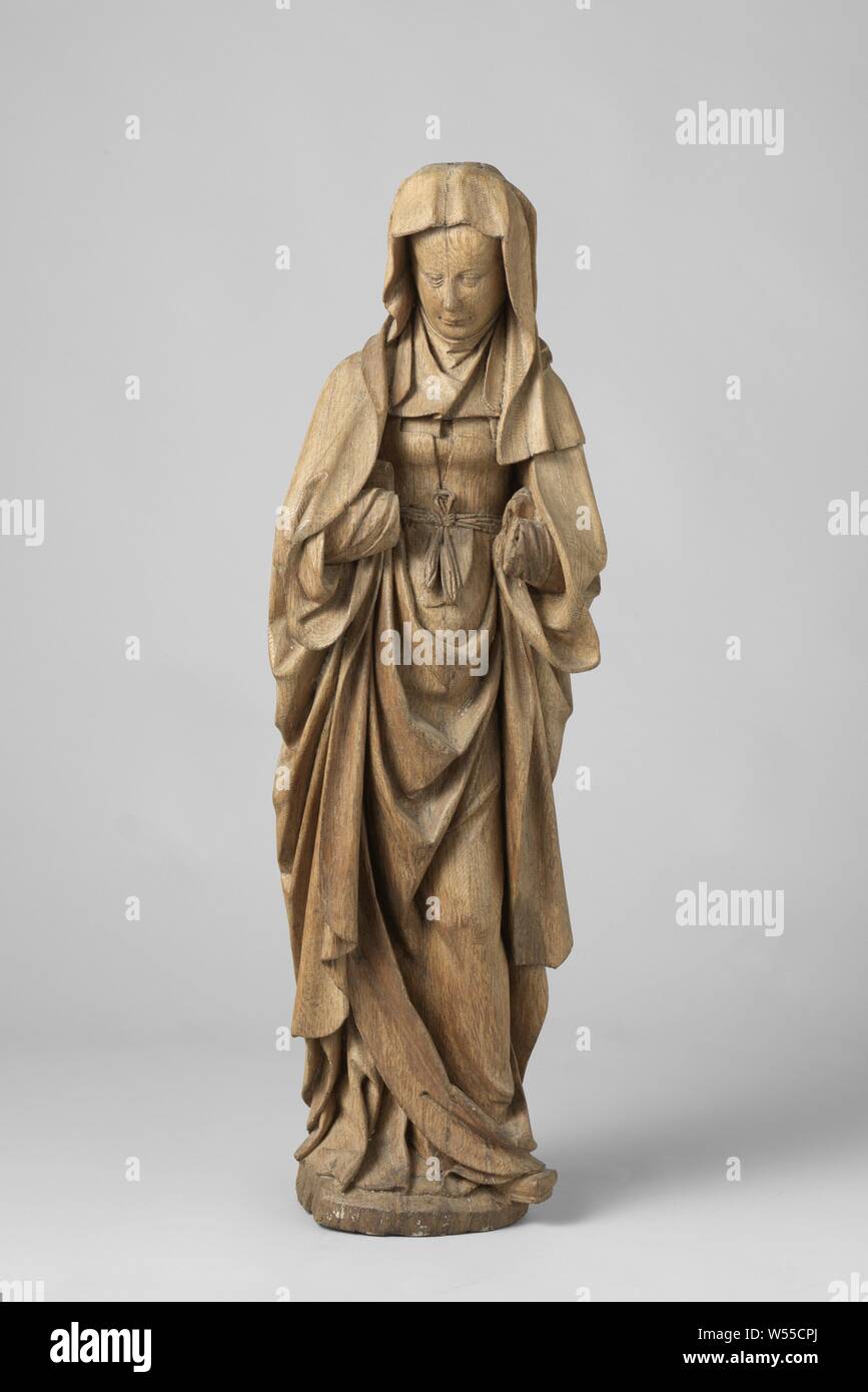 Die Jungfrau Maria und der hl. Johannes der Evangelist, Maria aus einer Kreuzigungsgruppe, Maria steht mit leicht ihren Kopf drehte sich zu dem auf einer ovalen Boden, ihre linke Schuh toe nach außen zeigen. Sie trägt ein Kleid mit einem tief geschnittene Jacke über es, ein Mantel, hält sie unter beide Arme, Augen eines Kindes und einen Schleier über den Kopf. um die Taille ist ein Riemen, der an der Vorderseite mit einer Schleife gebunden ist, aufrechte Figuren von Maria ohne das Christuskind, Arnt van Tricht, Nederrijn, C. 1540 - C. 1545, Eiche (Holz), h 100 cm Stockfoto