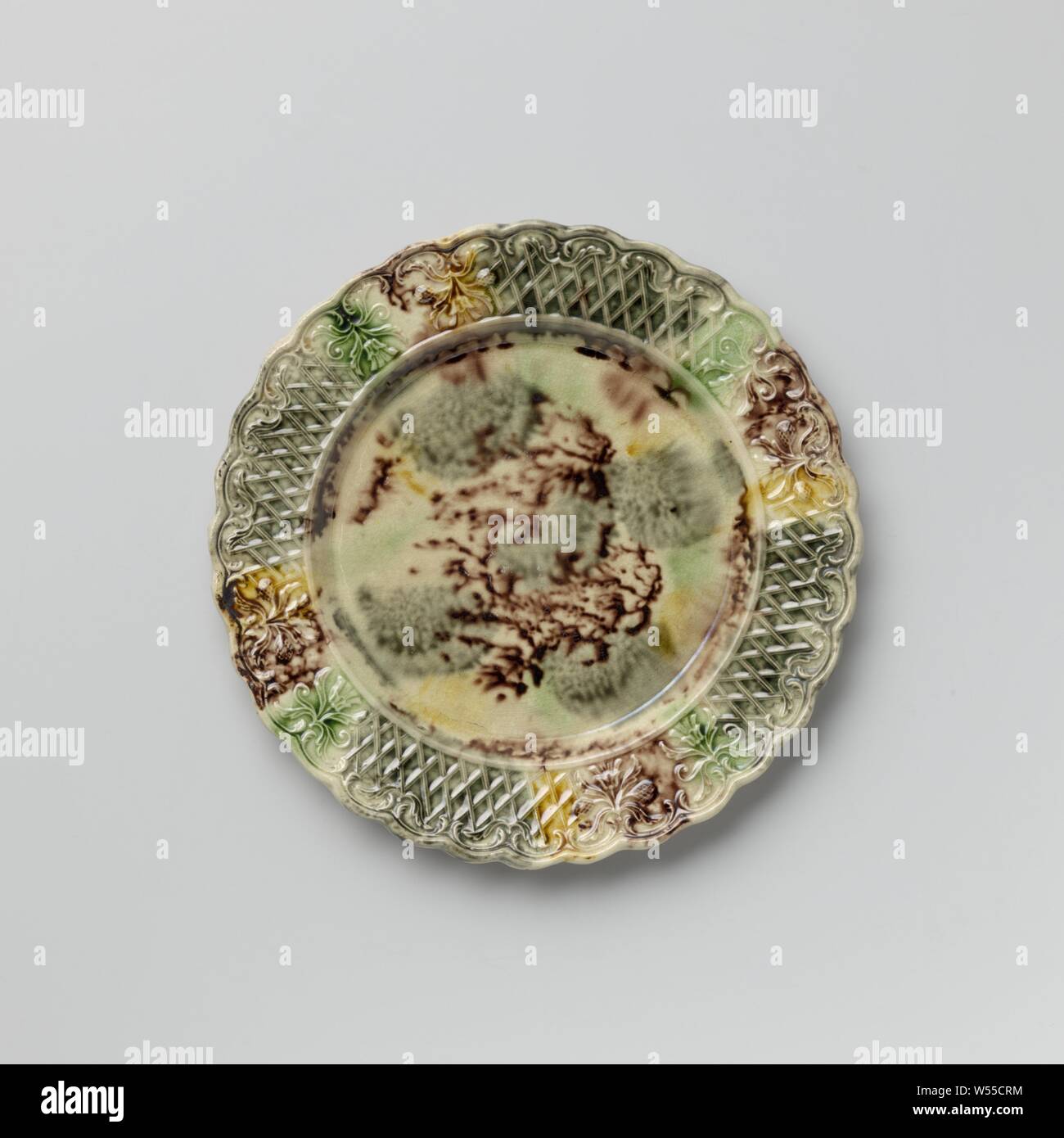Platte von bunten Hard- abgefeuert, Steingut, Staffordshire, Platte von bunten Hard- feuerte Steingut. Die Grenze ist mit Verzierung, mit zwei symmetrischen floralen Mustern durchsetzt geprägte nebeneinander platziert. Die gekerbte Kante ist auf der Innenseite mit Voluten und Blattmotiven dekoriert. Die Platte ist mit eine gefleckte führen in Mangan Glasur, Grün, Grau und Gelb. Der Rücken ist in Mangan punktiert und hat einen Fuß Flanke, anonym, England, C. 1750 - C. 1780, Steingut, führen Glasur, h 1,6 cm x T 19,3 cm Stockfoto