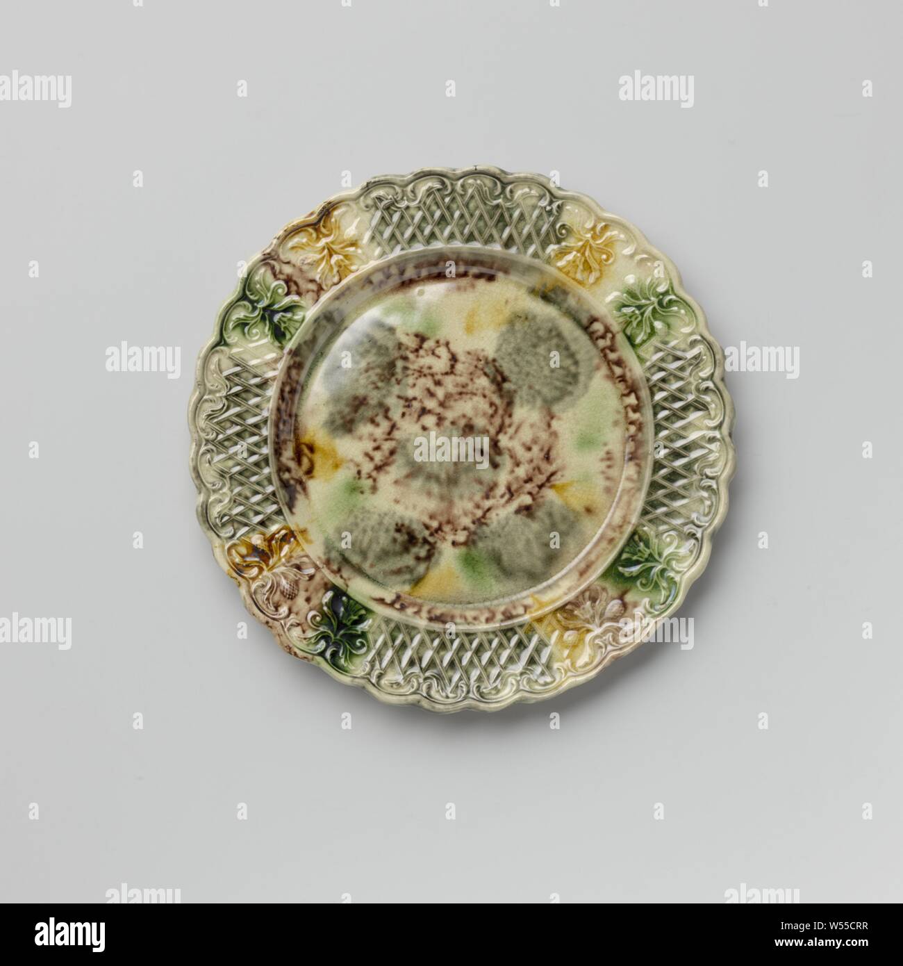 Platte von bunten Hard- abgefeuert, Steingut, Staffordshire, Platte von bunten Hard- feuerte Steingut. Die Grenze ist mit Verzierung, mit zwei symmetrischen floralen Mustern durchsetzt geprägte nebeneinander platziert. Die gekerbte Kante ist auf der Innenseite mit Voluten und Blattmotiven dekoriert. Die Platte ist mit eine gefleckte führen in Mangan Glasur, Grün, Grau und Gelb. Der Rücken ist in Mangan punktiert und hat einen Fuß Flanke, anonym, England, C. 1750 - C. 1780, Steingut, führen Glasur, h 1,6 cm x T 19,3 cm Stockfoto