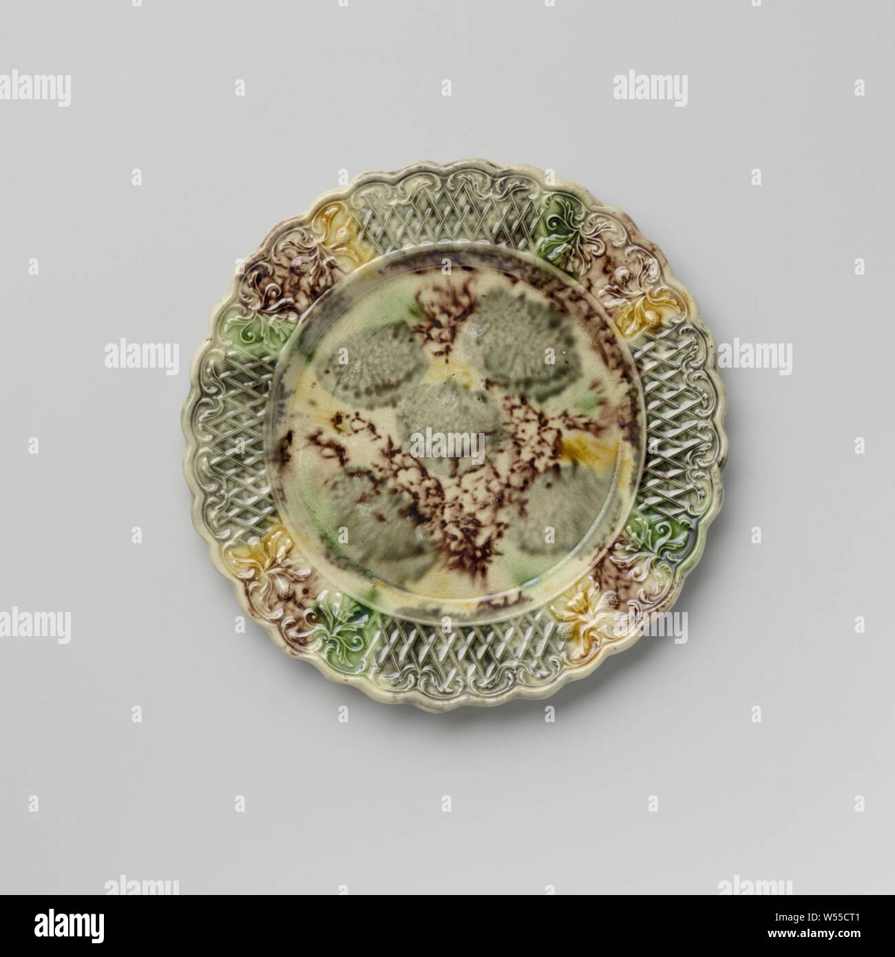Platte von bunten Hard- abgefeuert, Steingut, Staffordshire, Platte von bunten Hard- feuerte Steingut. Die Grenze ist mit Verzierung, mit zwei symmetrischen floralen Mustern durchsetzt geprägte nebeneinander platziert. Die gekerbte Kante ist auf der Innenseite mit Voluten und Blattmotiven dekoriert. Die Platte ist mit eine gefleckte führen in Mangan Glasur, Grün, Grau und Gelb. Der Rücken ist in Mangan punktiert und hat einen Fuß Flanke, anonym, England, C. 1750 - C. 1780, Steingut, führen Glasur, h 1,6 cm x T 19,3 cm Stockfoto