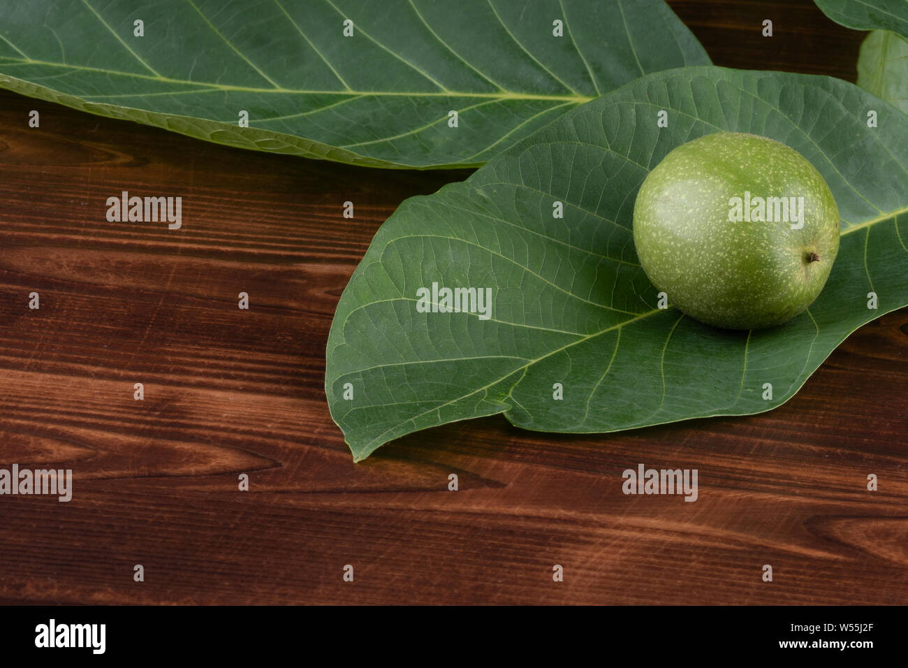 Grüne Walnuss auf ein Blatt, auf einer hölzernen Hintergrund. Stockfoto