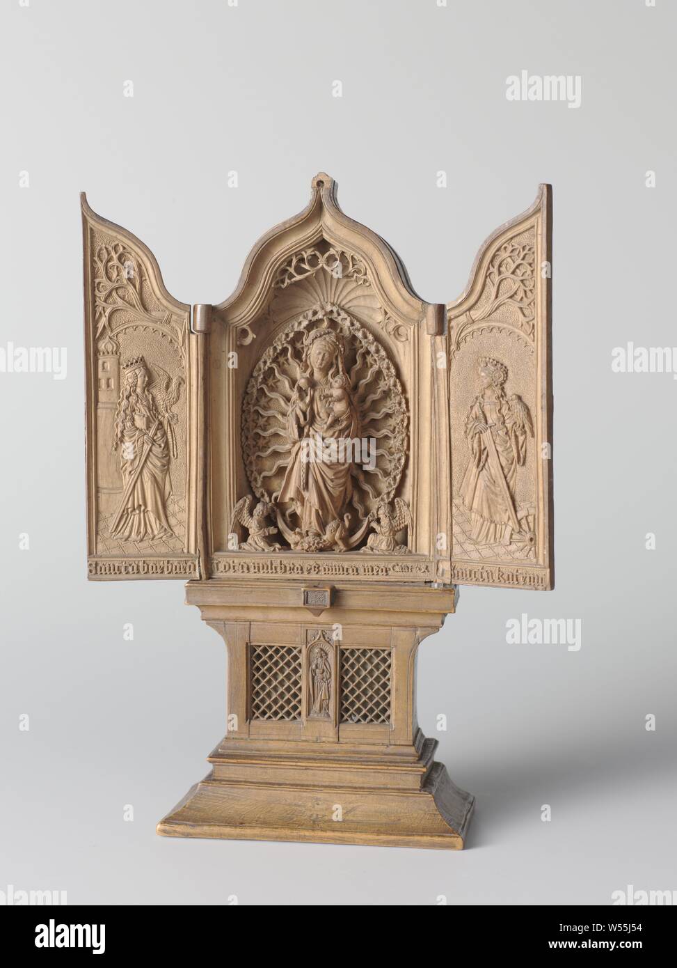 Triptychon Miniatur altar Hausaltar oder Reisen Altar mit Maria mit Kind, der Hl. Barbara und Katharina, Hausaltar oder Reisen Altar flankiert aus Palm Holz mit geschnitzten Darstellungen. Mittlerer Teil: Maria in Halo und mandorla mit dem Jesuskind auf dem Arm, in der geöffneten Seitenflügeln links St. Barbara, St. Anna. Die Außenseiten der Flügel mit St. Christoffel auf der linken und St. Joris auf der rechten Seite. Unter Maria den Text: Tota pulchra ES AMICA MEA. Auf dem Podest ein Relief von Johannes der Evangelist und ein Transenna. Auf der Rückseite zwei Türen, bin arianum', Madonna im strahlenkranz oder mandorla Stockfoto