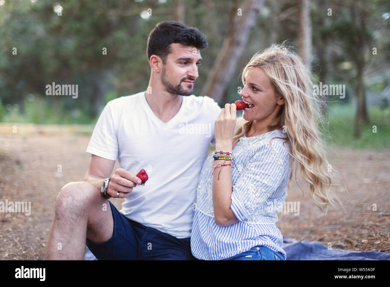 Glückliches junges Paar essen Erdbeere auf Picknick in der Natur Stockfoto