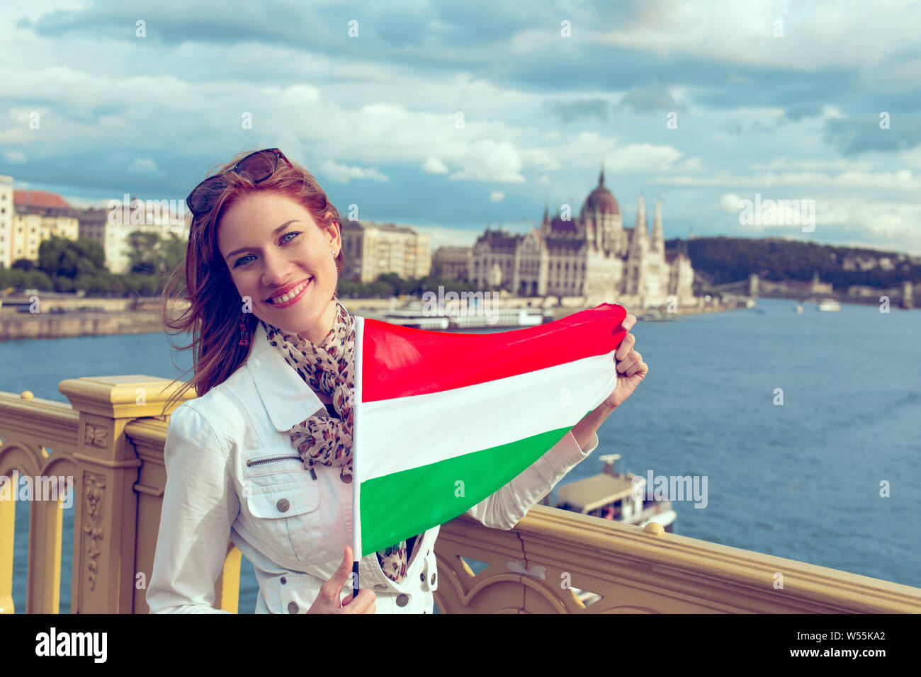 Glückliche junge Rothaarige ungarischen Urban woman holding ungarische Flagge in Budapest, toothy Lächeln Stockfoto