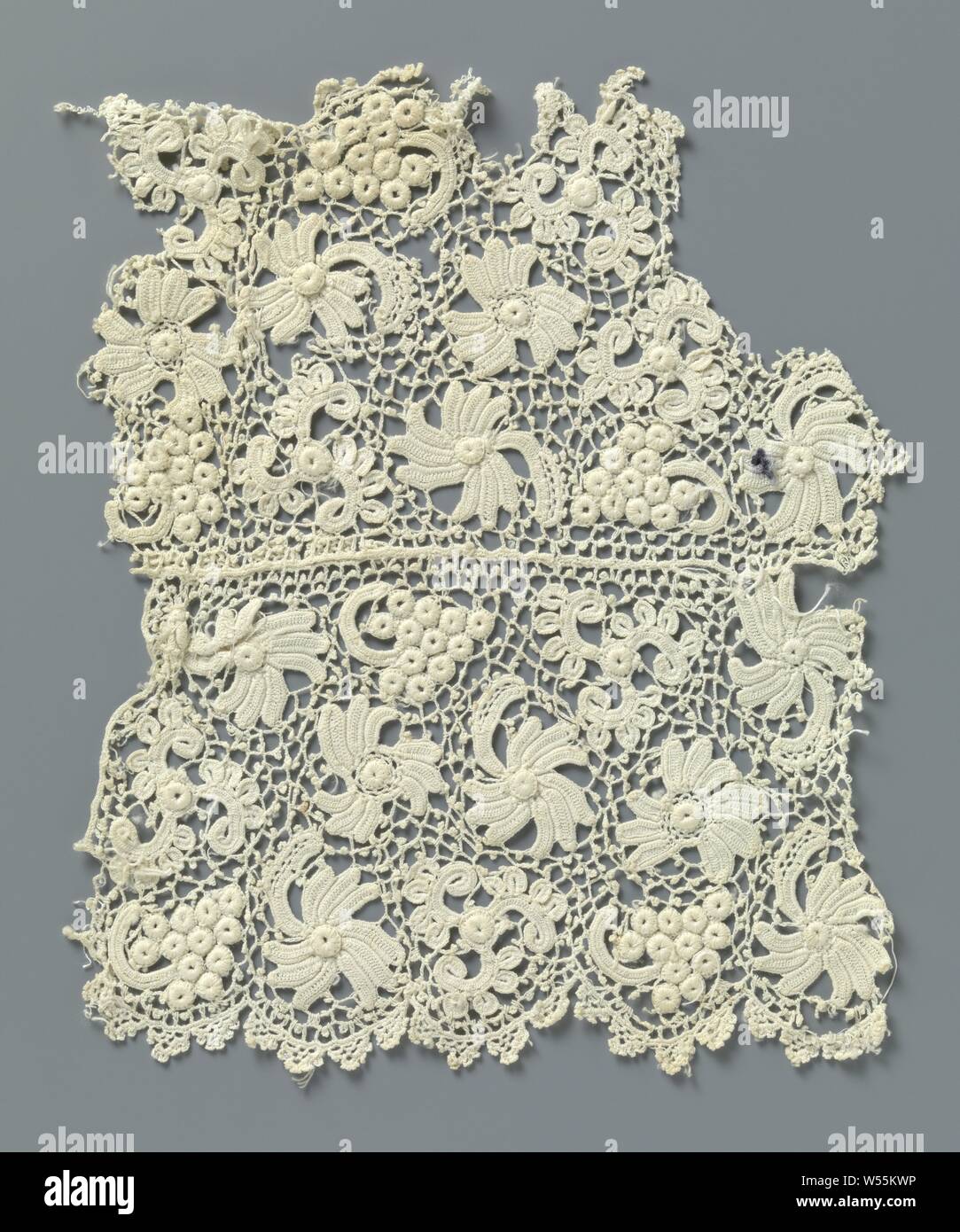 Fragment gehäkelter Spitze mit Blumen und Trauben, V-förmige Teil ein Stück naturfarbene Irischen gehäkelter Spitze. Muster mit Blumen und Trauben und einem gestricken unregelmäßigen Gitter mit Picots. Auf der Außenseite, die halbrunde Jakobsmuscheln mit iconic Bogen gesetzt. Die verschiedenen Teile der Kanten sind noch nicht abgeschlossen und/oder geschnitten oder getrimmt., anonym, Ierland (möglicherweise), C. 1890 - C. 1909, Baumwolle (Textil), L 21,5 cm x W 18,5 cm Stockfoto