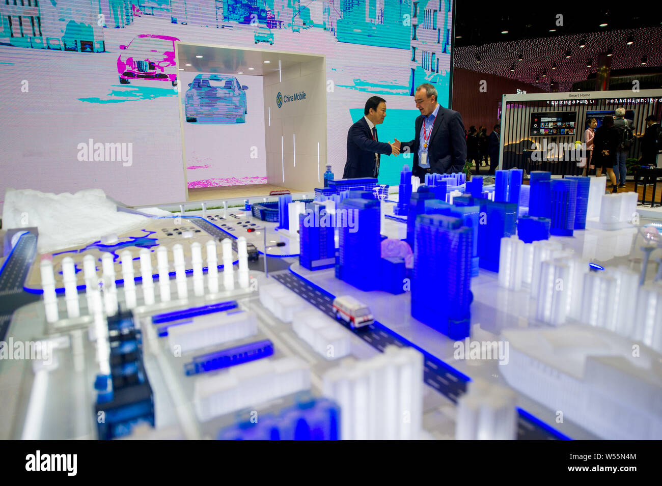 Ein chinesischer Aussteller schüttelt Hände mit einem Besucher am Stand von China Mobile während des Mobile World Congress (MWC 2019 19) in Barcelona, Spanien, 25. Feb. Stockfoto