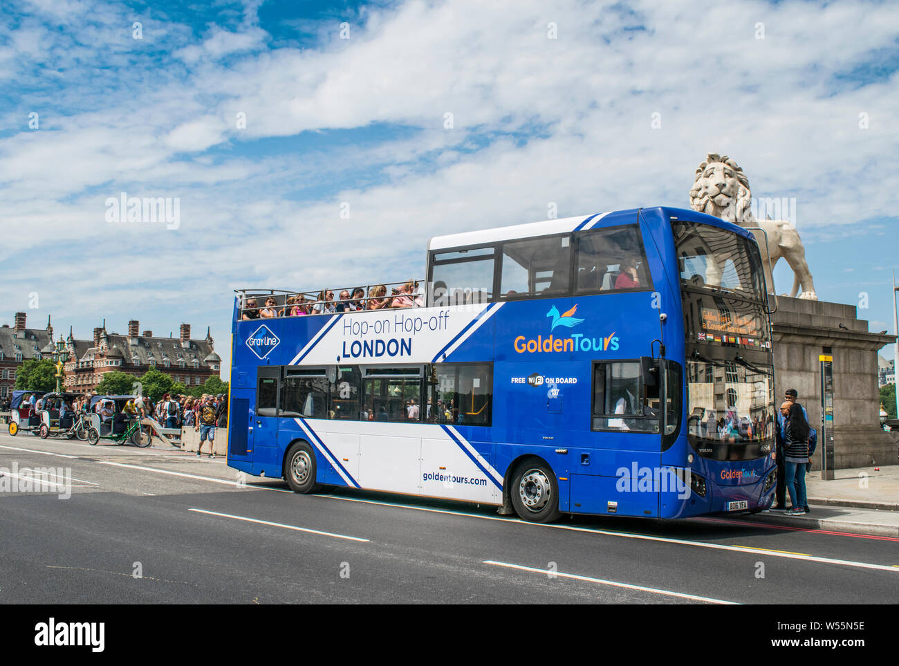 Golden Tours Double Decker sightseeing tour bus herauf Touristen an der Bushaltestelle an der Westminster Bridge, London mit Rikscha und South Bank Lion Stockfoto