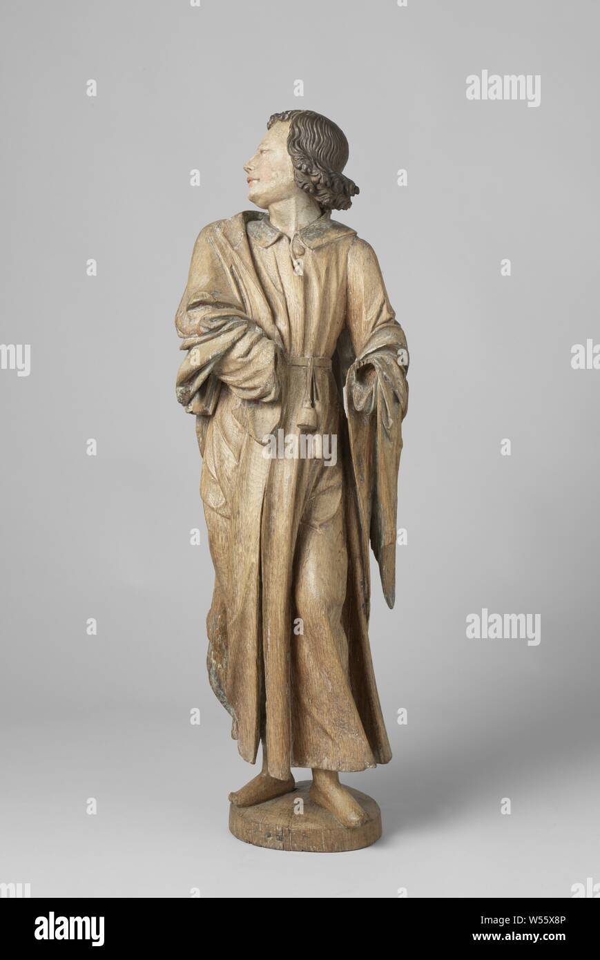 Die Jungfrau Maria und der hl. Johannes der Evangelist Johannes von einer Kreuzigung, John steht auf dem rechten Bein mit dem linken Bein leicht nach vorn gebeugt auf einer Scheibenförmigen Erde. Der Kopf ist stark nach links und wieder zurück gedreht, der Blick nach oben geneigt. Er schellen ein Buch unter dem rechten Arm, leicht Holding die verbogene links vom Körper weg. Er trägt einen Kragen mit Knopf. Ein Riemen und eine Tasche für Schreibgeräte hängen an den Riemen, der Apostel Johannes der Evangelist, mögliche Attribute: Buch, Kessel, Chalet mit Schlange, Adler, Palm, Scrollen, Arnt van Tricht, Nederrijn, C. 1540 - C. 1545, Eiche (Holz), h 103.5 Stockfoto