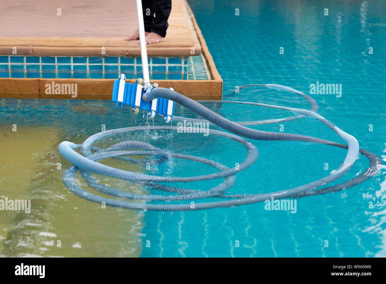 Arbeitnehmer Reinigung Schwimmbad mit den Unterdruckschlauch am Morgen. Stockfoto