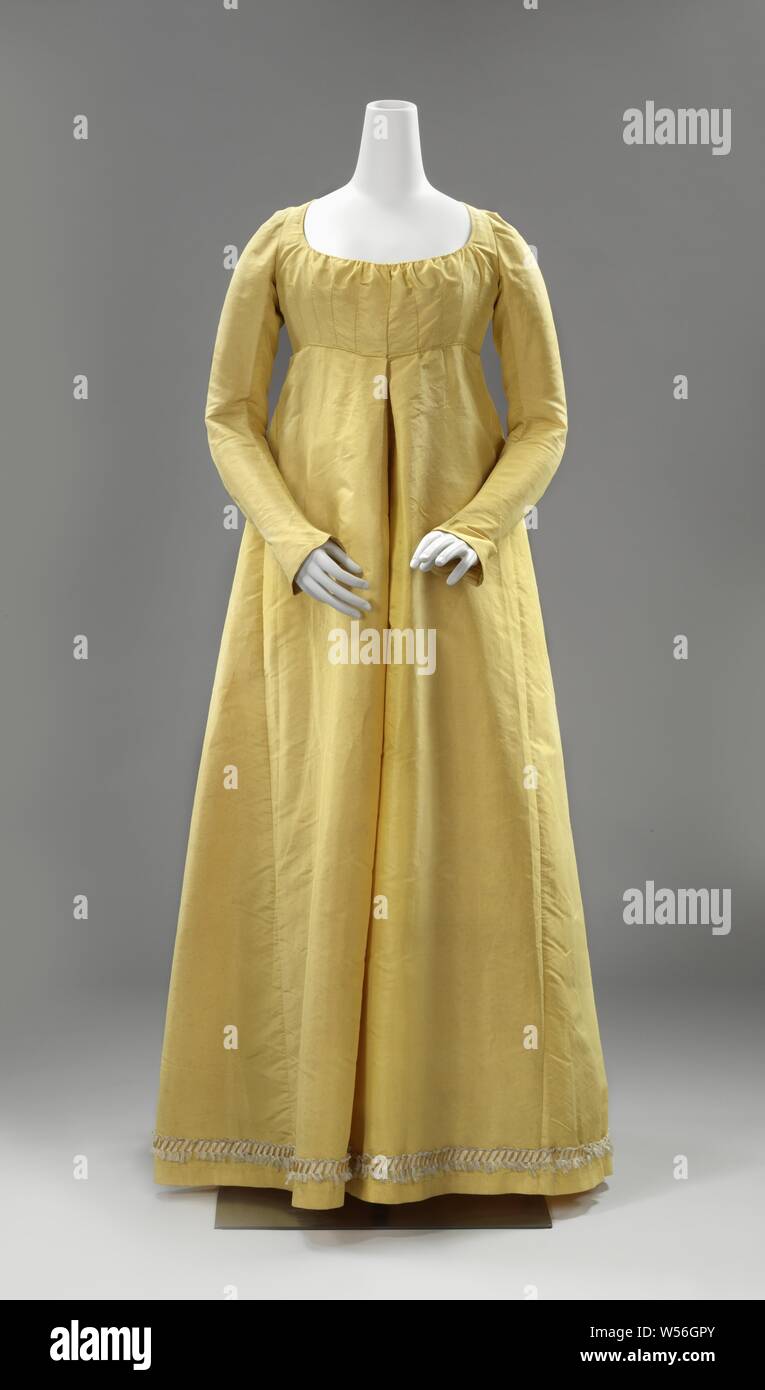 Kleid mit einem Diamanten - Rückseite geformt, kanariengelb Seidenkleid mit hoher Taille, Diamant-förmigen rücken einsetzen, lange Ärmel und mit einem weißen entlang der Rocksaum und gelbe Seide Garnituren mit Quasten, Troddeln, Oliven, Nüsse, kanariengelb Seide Gehrock mit hoher Taille, langen Ärmeln und getrimmt entlang der Rocksaum mit einem weißen und gelben Seide fransen trimmen. Modell: Der Hals hat einen runden Ausschnitt und einen Tunnel mit gelben Seidenband. Schließung in der Mitte vorne in hoher Taille durch den Tunnel mit geflochtenen gelb Seidenband. Vier vertikale Pfeile auf beiden Seiten der Split. Ärmel Schnitt diagonal auf den Faden, die ausgestellten über Stockfoto