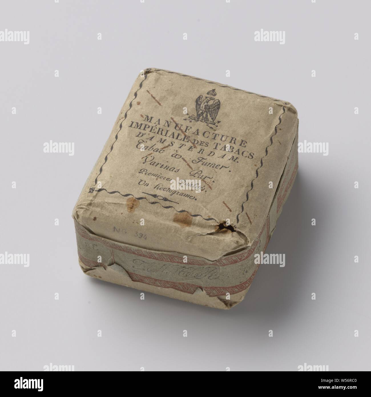 Régie - Tabak, in braunes Papier mit der französischen Sprache auf der einen Seite und niederländischer Sprache Inschrift auf der anderen, verpackt Tabak, Schließung von blau-grauem Papier mit roten Drucken bin anuf. Imperiale d'Amsterdam/Tabac à fumer, un-Hectogram" und Aufdruck in Schwarz (unleserlich) in einem roten Kartusche. Gekennzeichnet, Vorder-und Rückseite: Adler auf Bündel Pfeile unter Krone. Inschrift. Vorderseite: IMPERIAL TOBACCO FACTORY IN AMSTERDAM. Das Rauchen von Tabak. Reine Varinas. Erste Art. Eine hectogame. Rückwärtsgang: idem in französischer Sprache, Amsterdam, Keizerlijke Tabaks-Fabriek, 1810-1813, Papier, l 9,5 cm x B 8 cm x T 4,5 cm Stockfoto