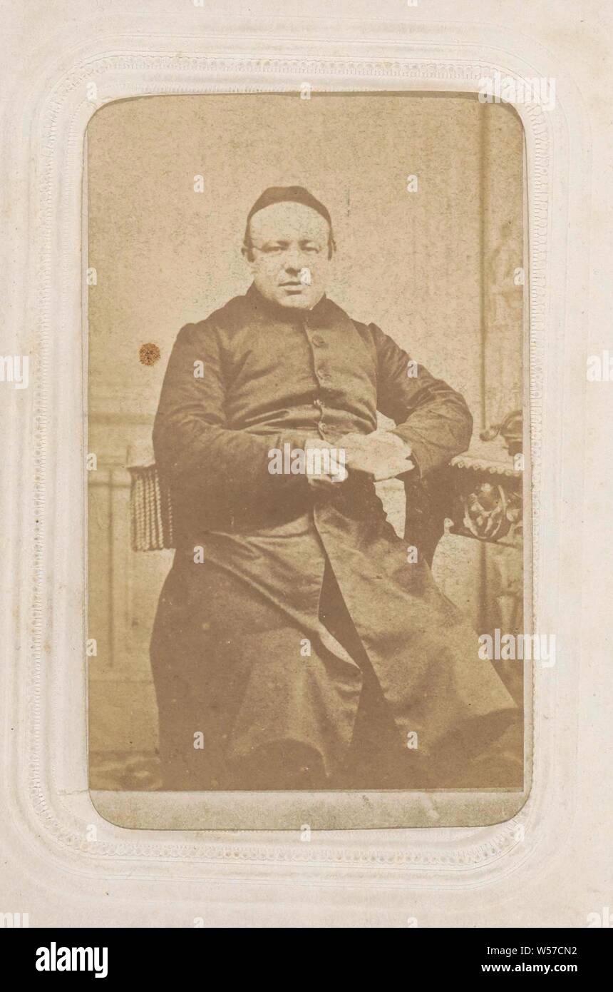 Porträt einer sitzenden Kleriker mit einem solo Video auf es und ein Buch in der Hand, Teil der Fotoalbum mit 26 Cartes-de-Visite van Römisch-katholischen Klerus, Priester (römisch-katholisch), Nijmegen, J.F. Huijbers, C. 1868 - C. 1893, Pappe, Papier, Fotopapier, Eiklar drucken, H 82 mm x B 49 mm Stockfoto