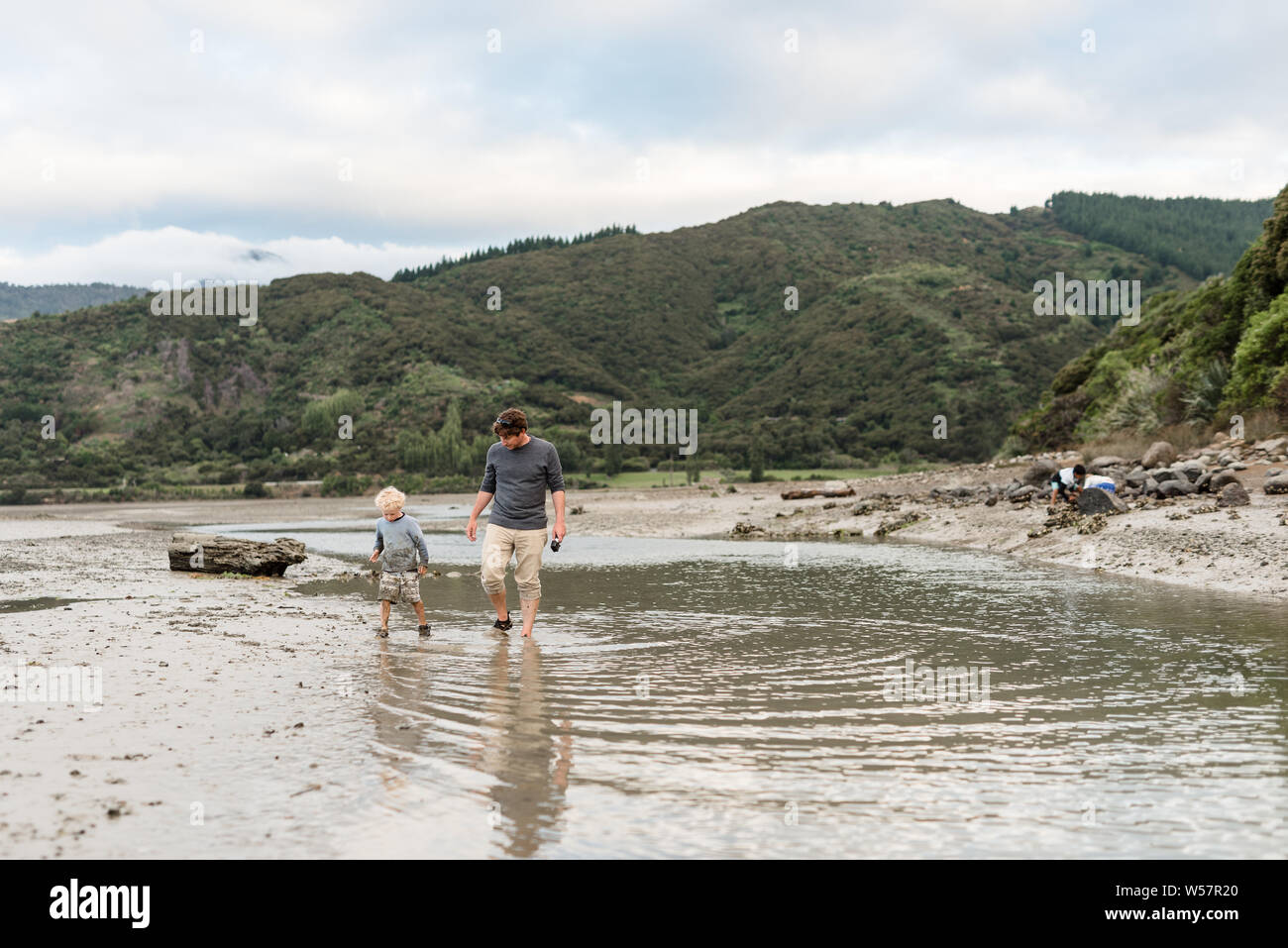 Vater und Sohn gehen im flachen Wasser in Neuseeland Stockfoto