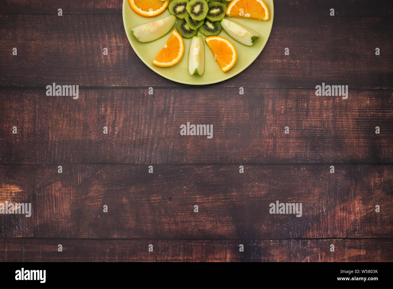 Grüne Platte mit frischem Obstsalat auf dem hölzernen Tisch Stockfoto