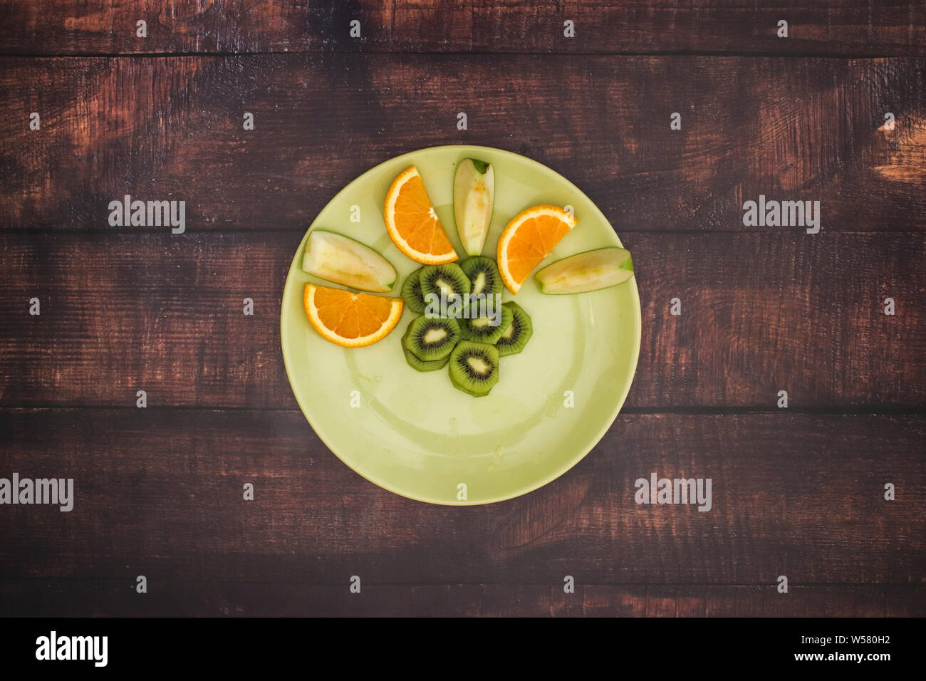 Grüne Platte mit frischem Obstsalat auf dem hölzernen Tisch Stockfoto