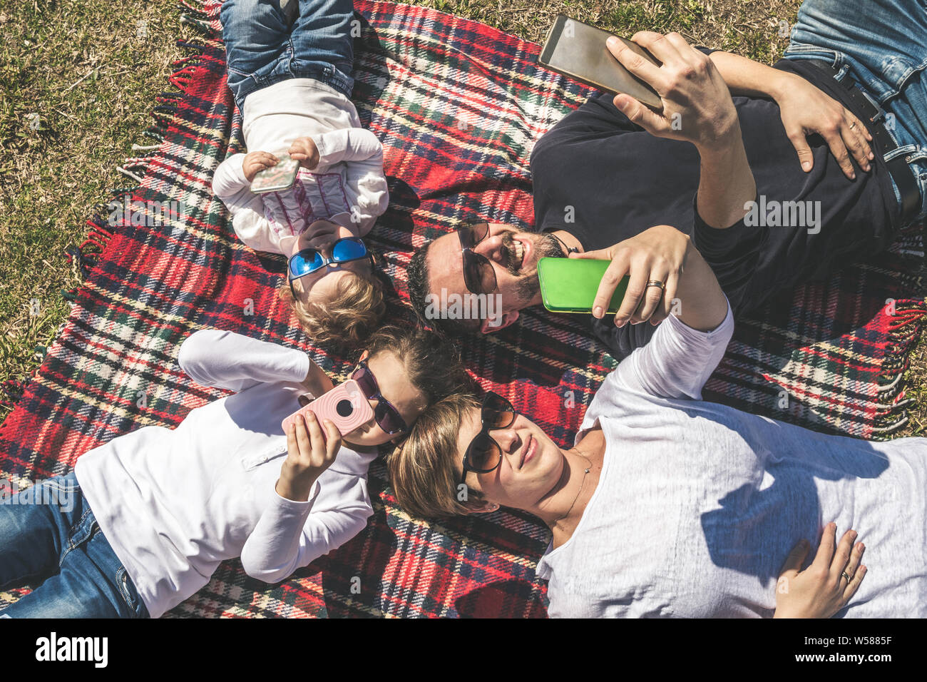 Junge, glückliche Familie spielt selfies mit Mobiltelefonen. Mama, Papa und zwei kleinen Töchtern Witz mit Sonnenbrille amüsiert und Chat untereinander. Konzept o Stockfoto