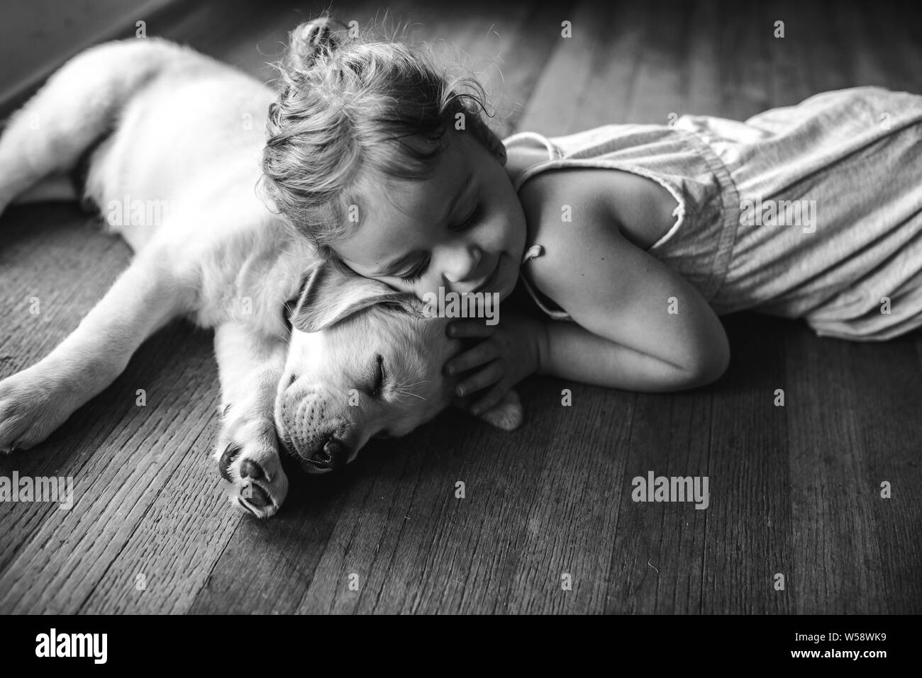 Schlafen gelben Labrador lab Welpen Kuscheln mit kleinen Mädchen Stockfoto