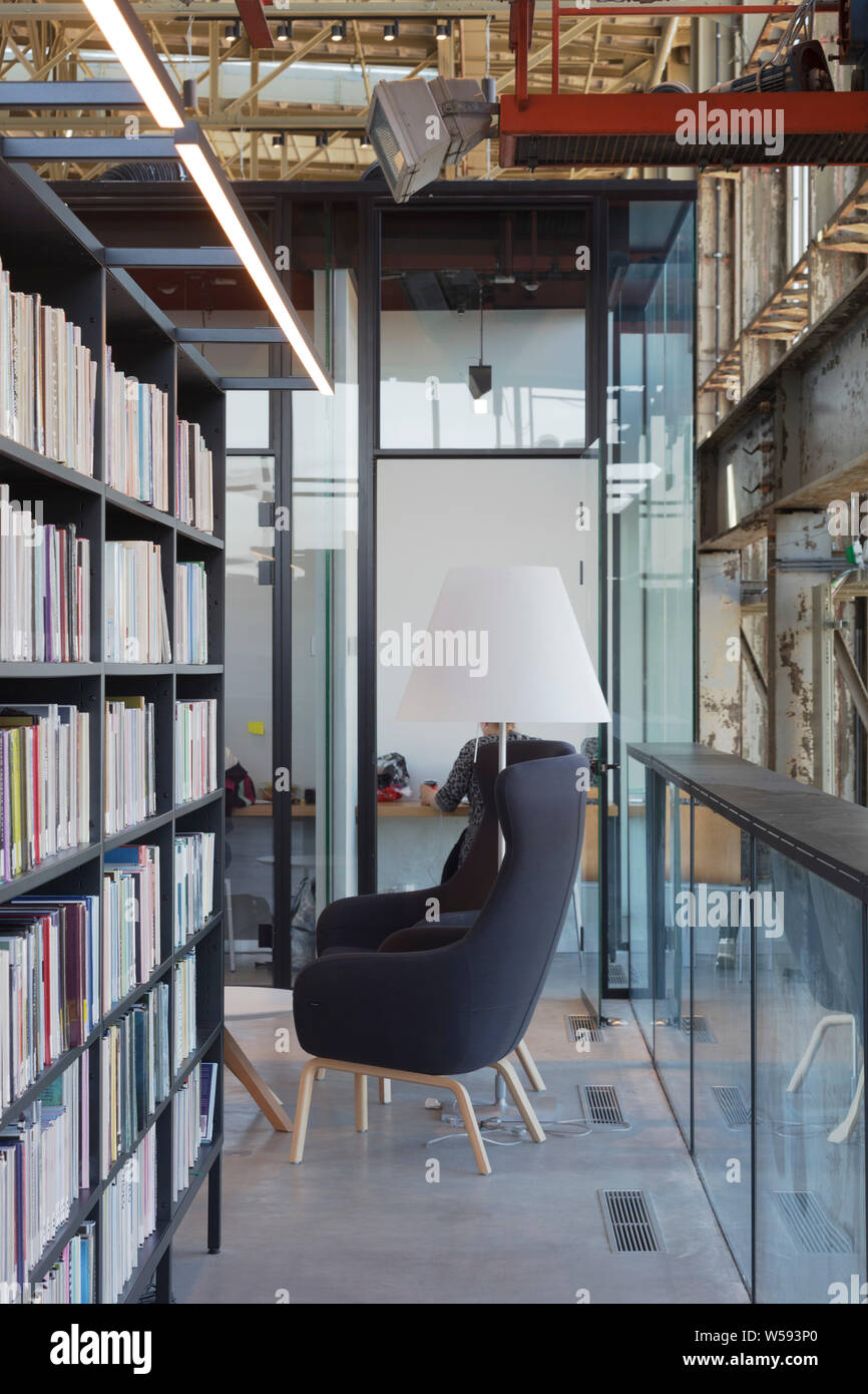 Bücherregale mit Studie cubicle hinter und grau Stuhl im Vordergrund. Bibliotheek LocHal, Tilburg, Niederlande. Architekt: CIVIC Architekten/Braaksma Stockfoto