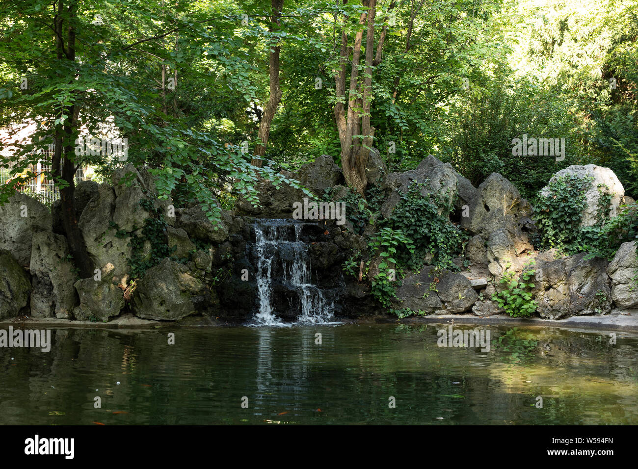 Ein Teich mit einem kleinen Wasserfall im Park (Liechtensteinpark