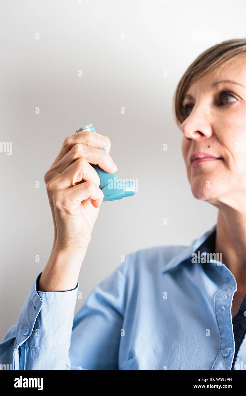 Frau mit einem Inhalator einen Asthmaanfall zu behandeln. Der Inhaler enthält bronchienerweiternde Medikamente, die verengten Atemwege in der Lunge zu erweitern. Stockfoto