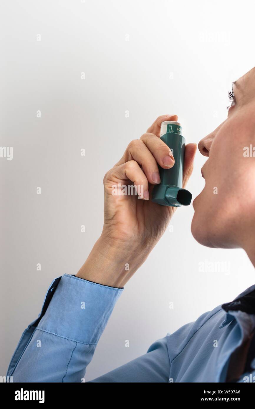 Frau mit einem Inhalator einen Asthmaanfall zu behandeln. Der Inhaler enthält bronchienerweiternde Medikamente, die verengten Atemwege in der Lunge zu erweitern. Stockfoto