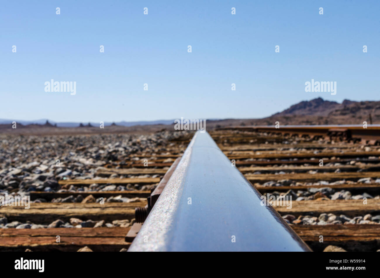 Glänzend stahl schiene, die zum Horizont unter blauem Himmel. Low Angle View betont die flache glänzende Schiene. Stockfoto