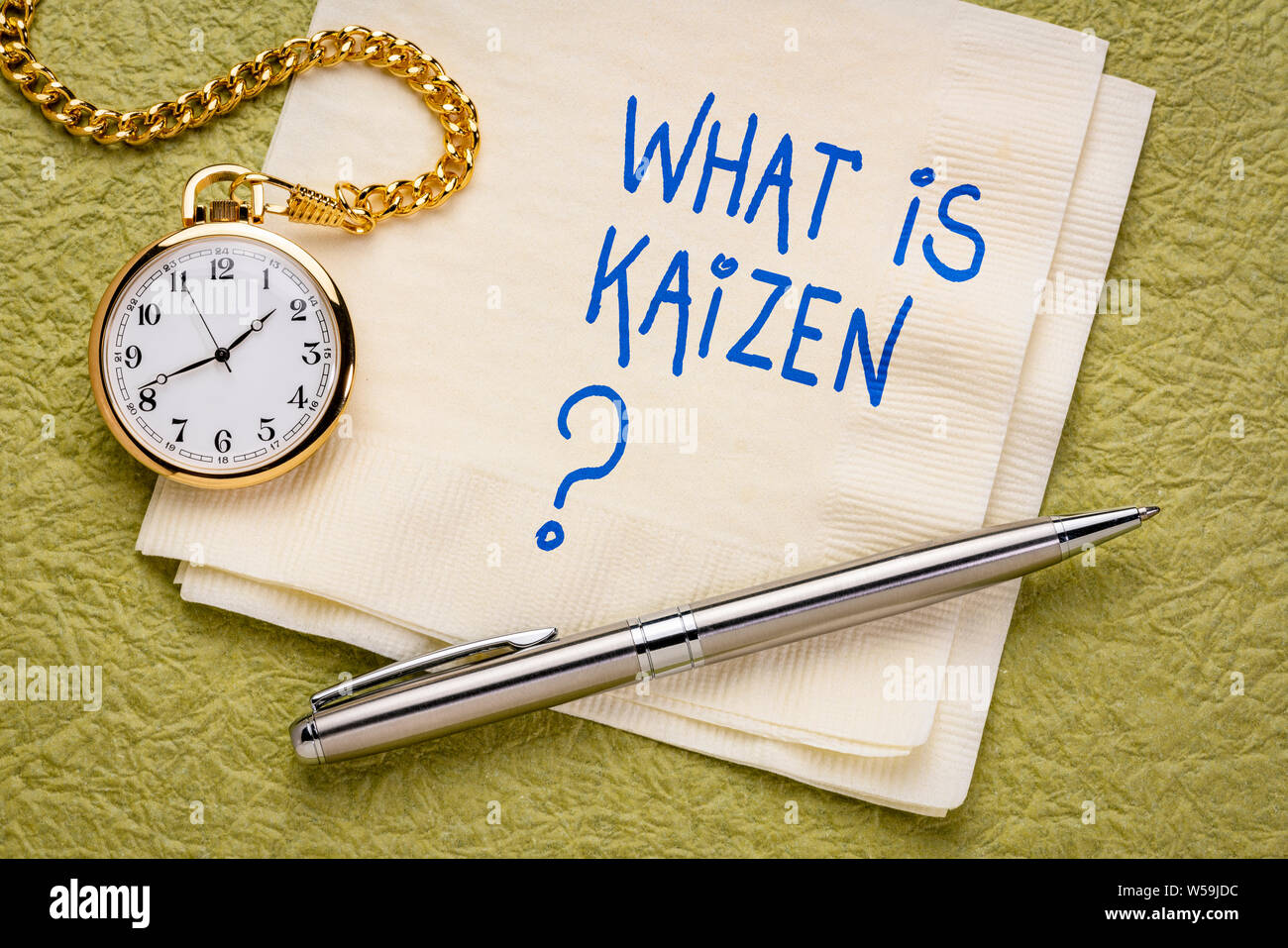 Was ist Kaizen? Japanische kontinuierliche Verbesserung Konzept - Handschrift auf eine Serviette mit einer Taschenuhr. Stockfoto