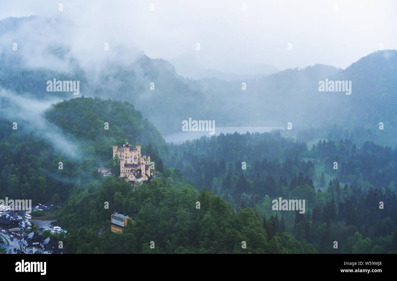 Panoramablick Kiefernwald und Schloss Hohenschwangau mit nebligen Umfeld in Deutschland Stockfoto