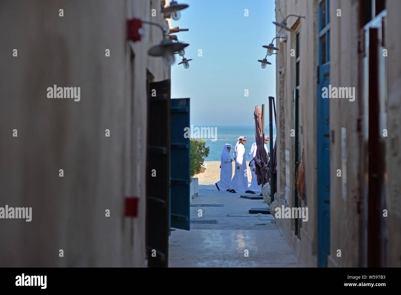AL WAKRAH, Katar - Februar 5, 2016: Drei qatari Männer wandern Sie an der Küste der Wakrah old Souq. Am Ende eines Winters Nachmittag Stockfoto