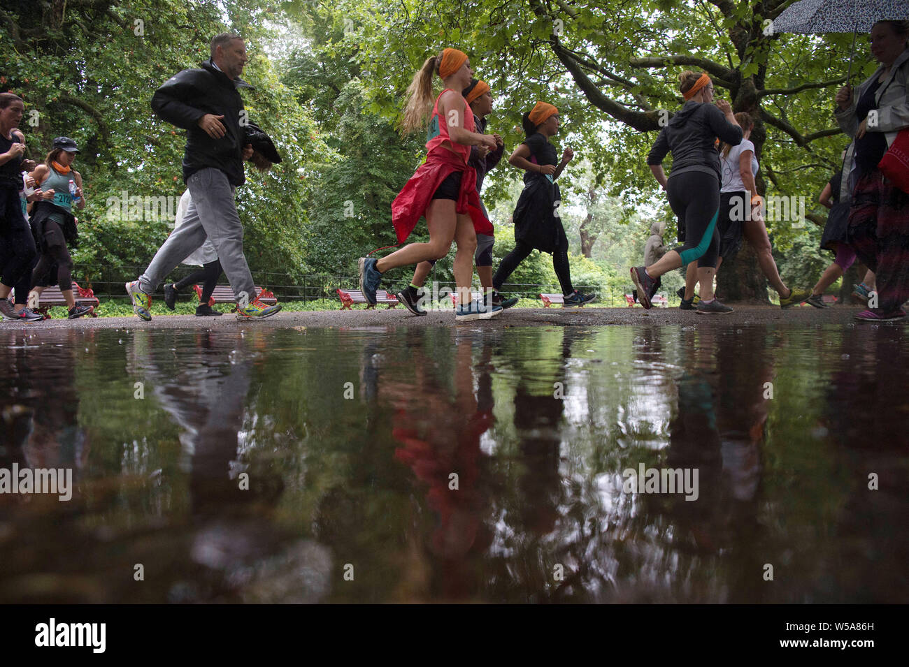 Die Menschen sind in einer Pfütze wider, wie sie Teil in einem Lauf in Battersea Park, London. Stockfoto