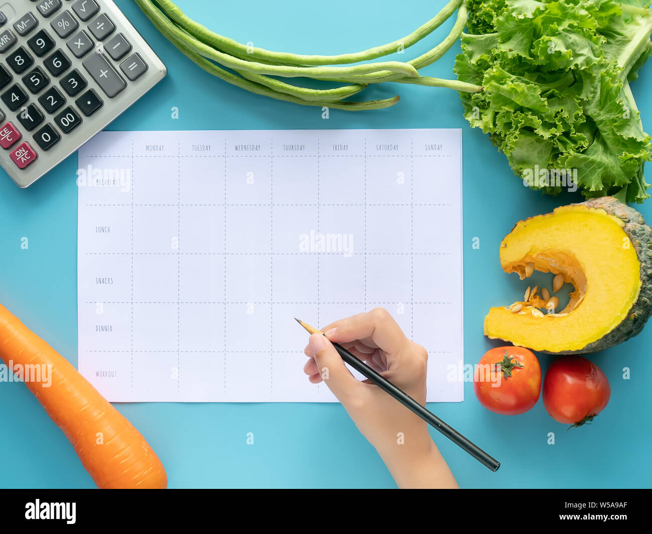 Kalorien, Speisen, Ernährung und Gewichtsabnahme Konzept. nach oben Blick von Hand ausfüllen Speisen auf leeres Papier mit Taschenrechner und Gemüse isolat Stockfoto