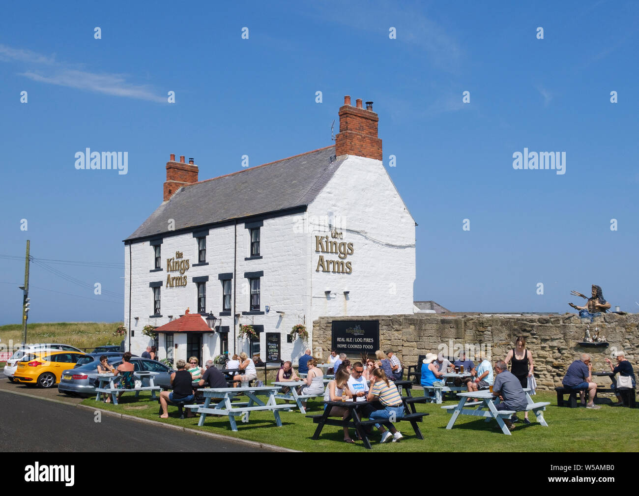 Kunden genießen Sie Drinks in während der Sitzung in der Sonne im Garten des Kings Arms Pub in Seaton Sluice Northumberland Stockfoto